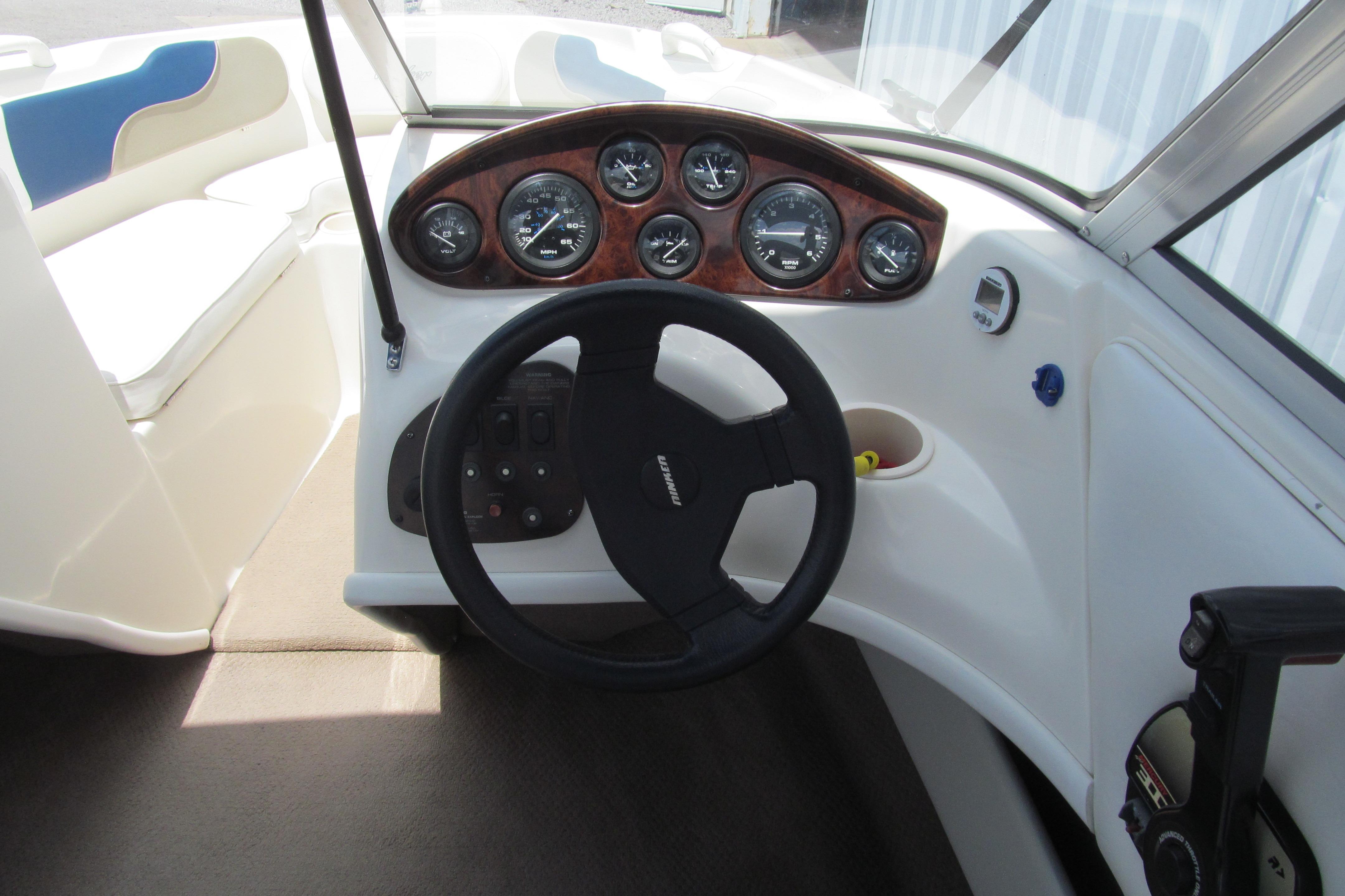 Steering wheel and dashboard of a 2000 Rinker boat, featuring multiple gauges and controls.