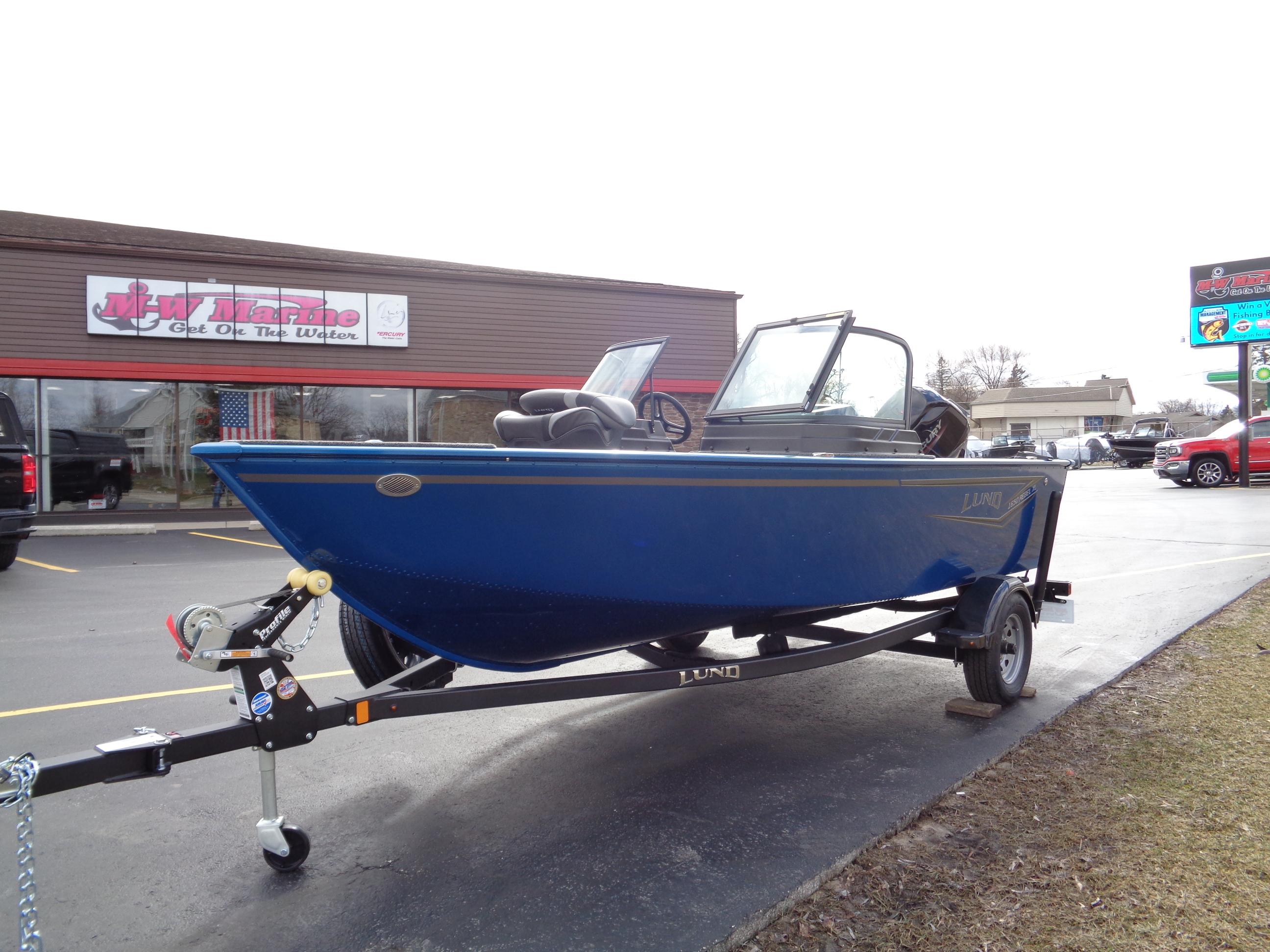 2024 Lund 1650 Rebel XL Sport boat on trailer, parked outside a store.