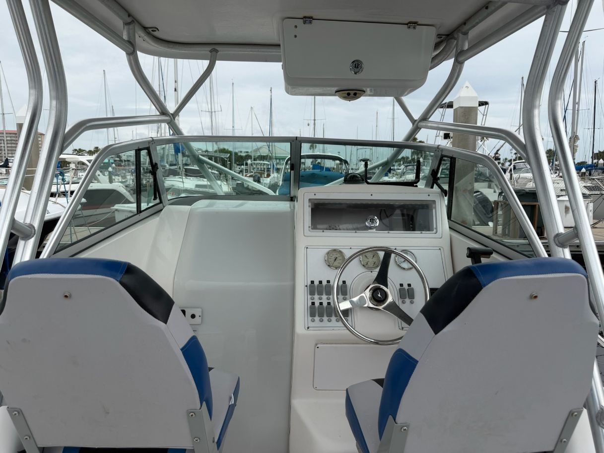 The image shows the cockpit of a 2003 Pro-Drive Walkaround boat in a marina.