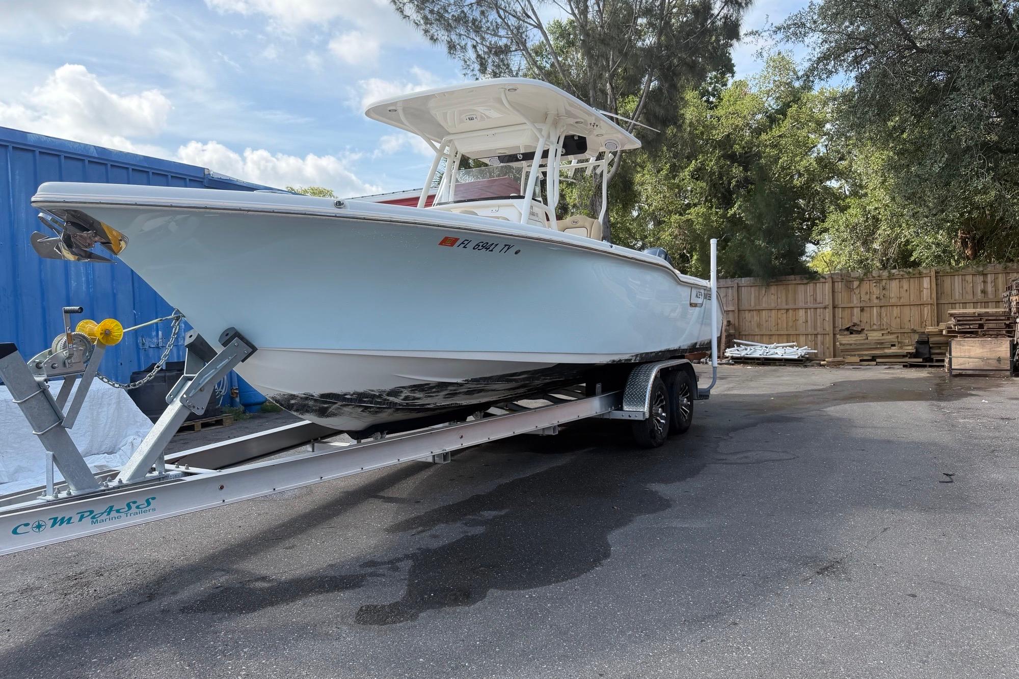 2019 Key West 263 FS boat on trailer, parked outdoors near trees and a blue container.