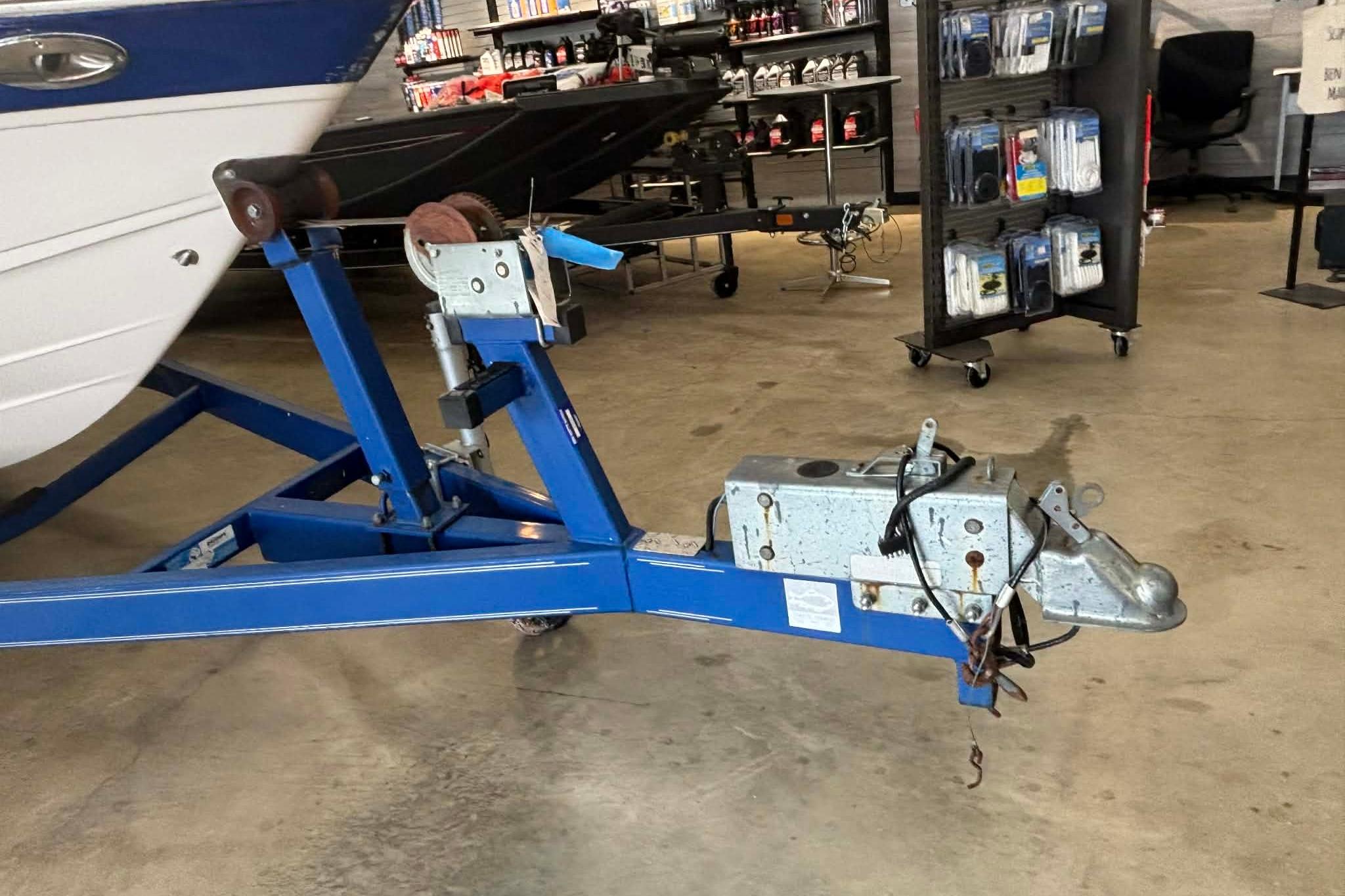 1999 Tide Craft Trophy Angler boat trailer in a showroom, featuring blue frame and winch.