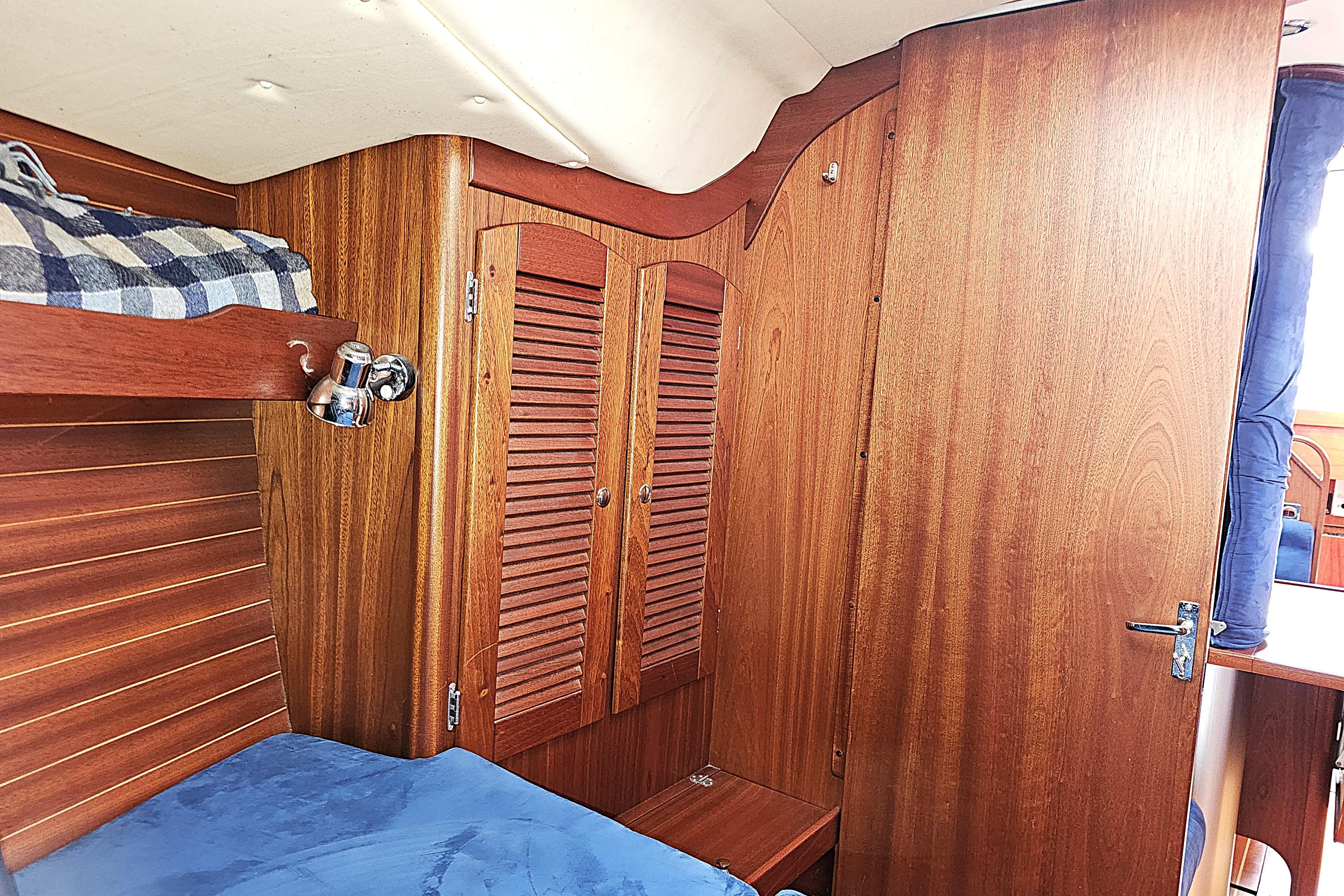 Interior of a 2006 Maxi 1100 sailboat with wooden cabinetry and cozy bedding.