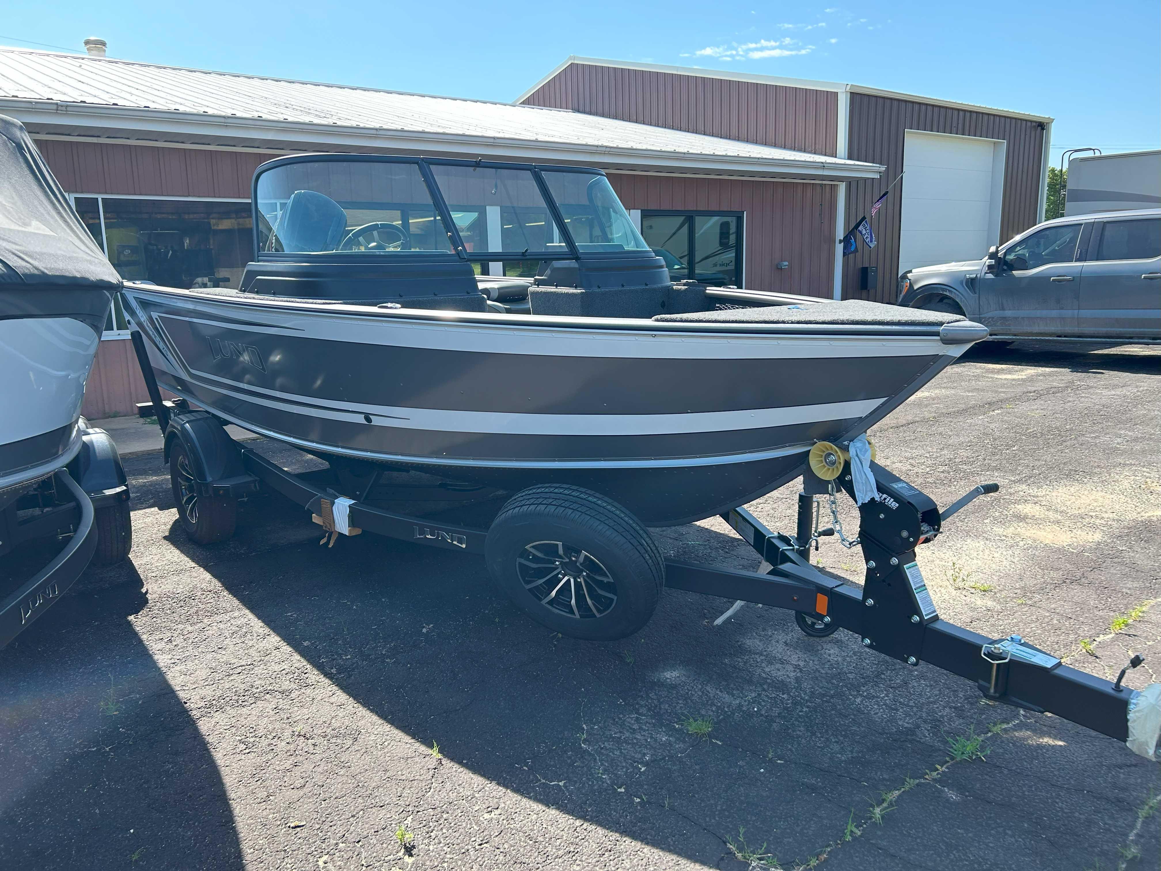 2025 Lund 1775 Impact XS boat on trailer, parked outside a building.
