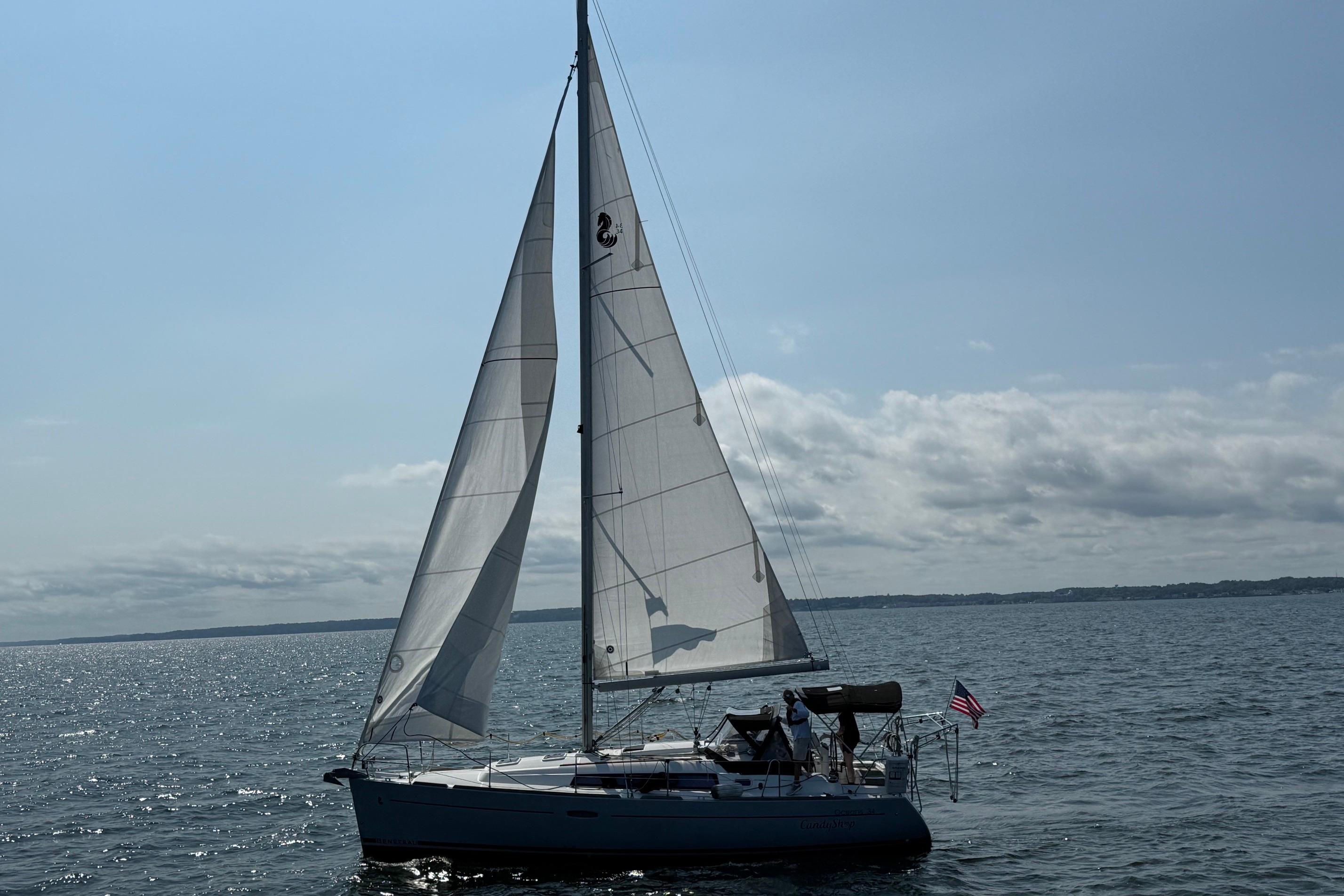 Sailing yacht Beneteau Oceanis 34, 2015 model, gliding on open water under clear skies.