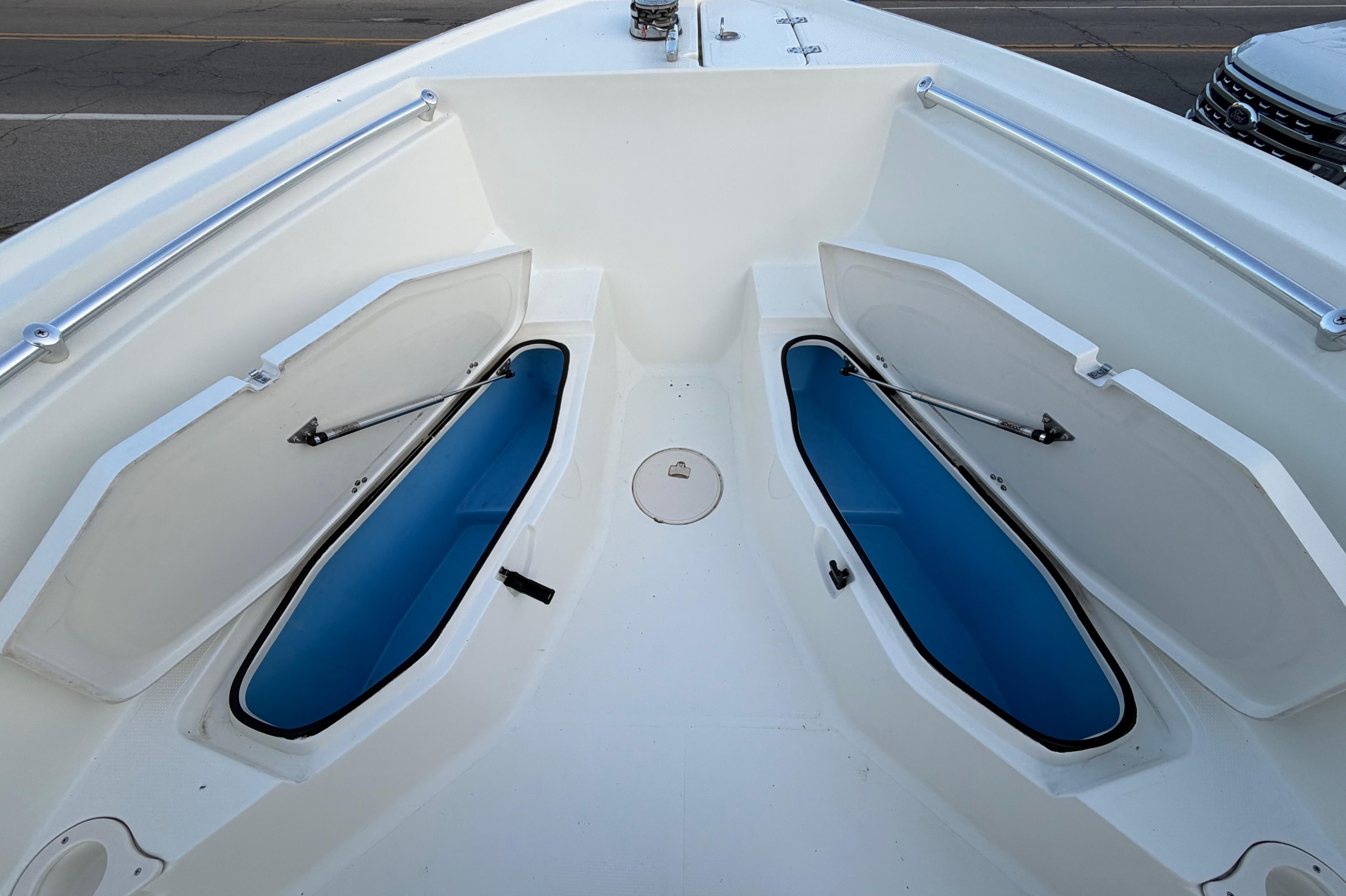 2007 Mako 234 Center Console boat with open storage compartments on deck.