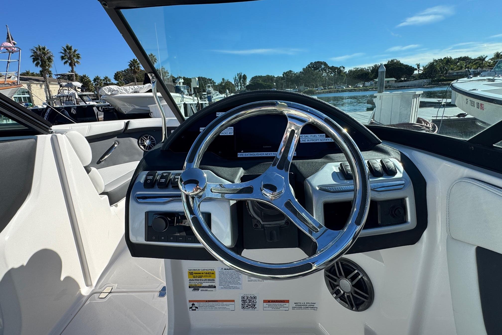 2026 Regal 21 OBX boat dashboard with steering wheel, docked in sunny marina.