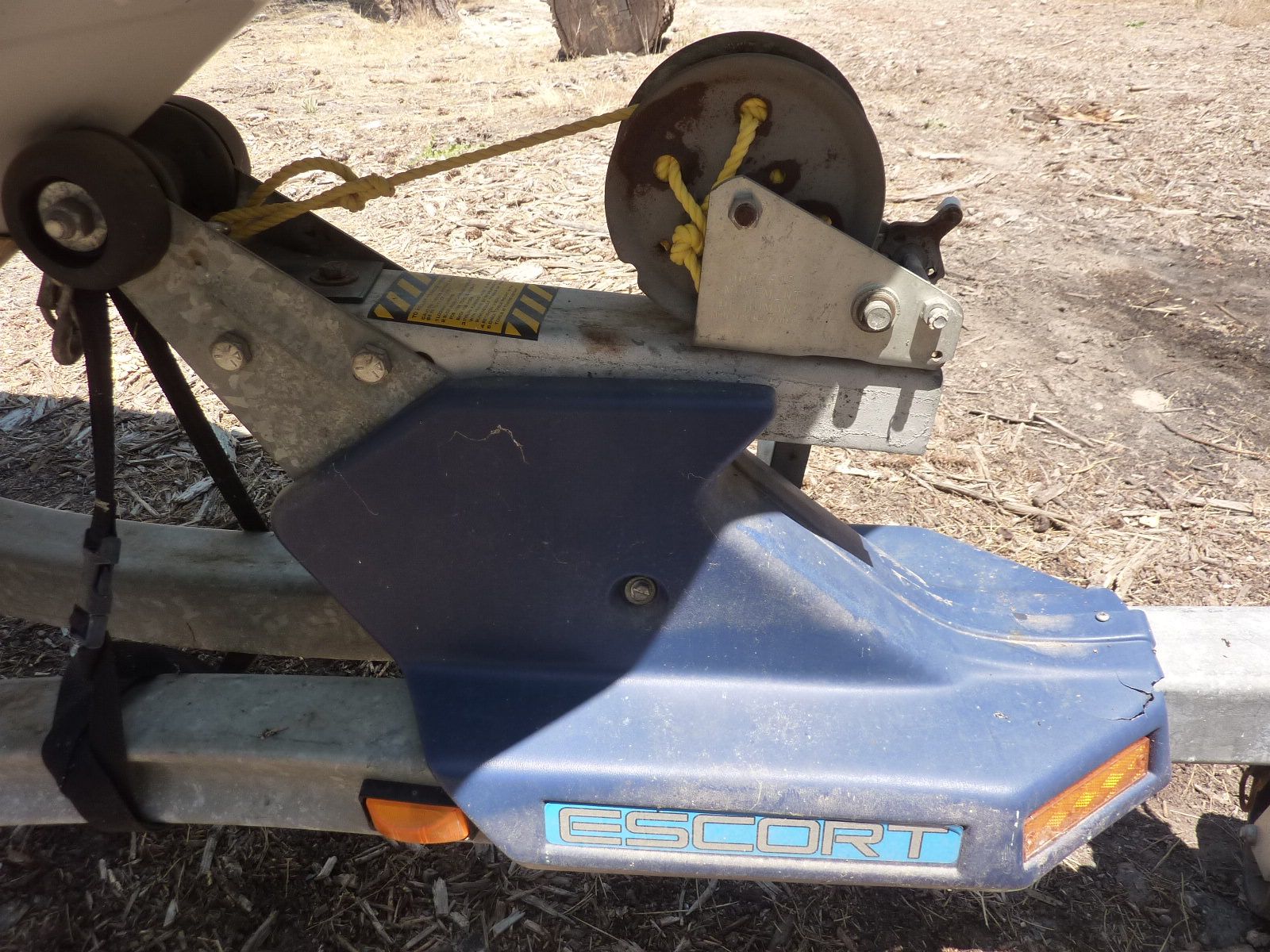 Close-up of a boat trailer with a winch and blue protective casing.