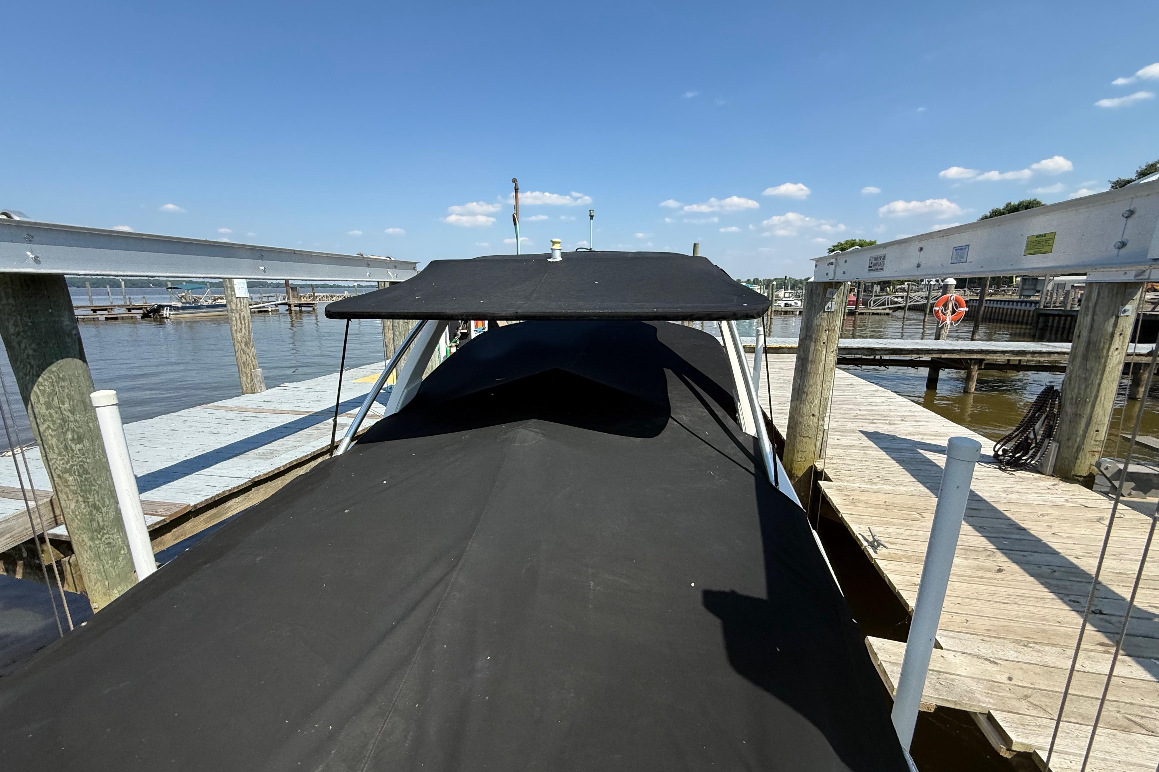 Covered 2011 Sea Ray 270 SLX boat docked at a marina under a clear blue sky.