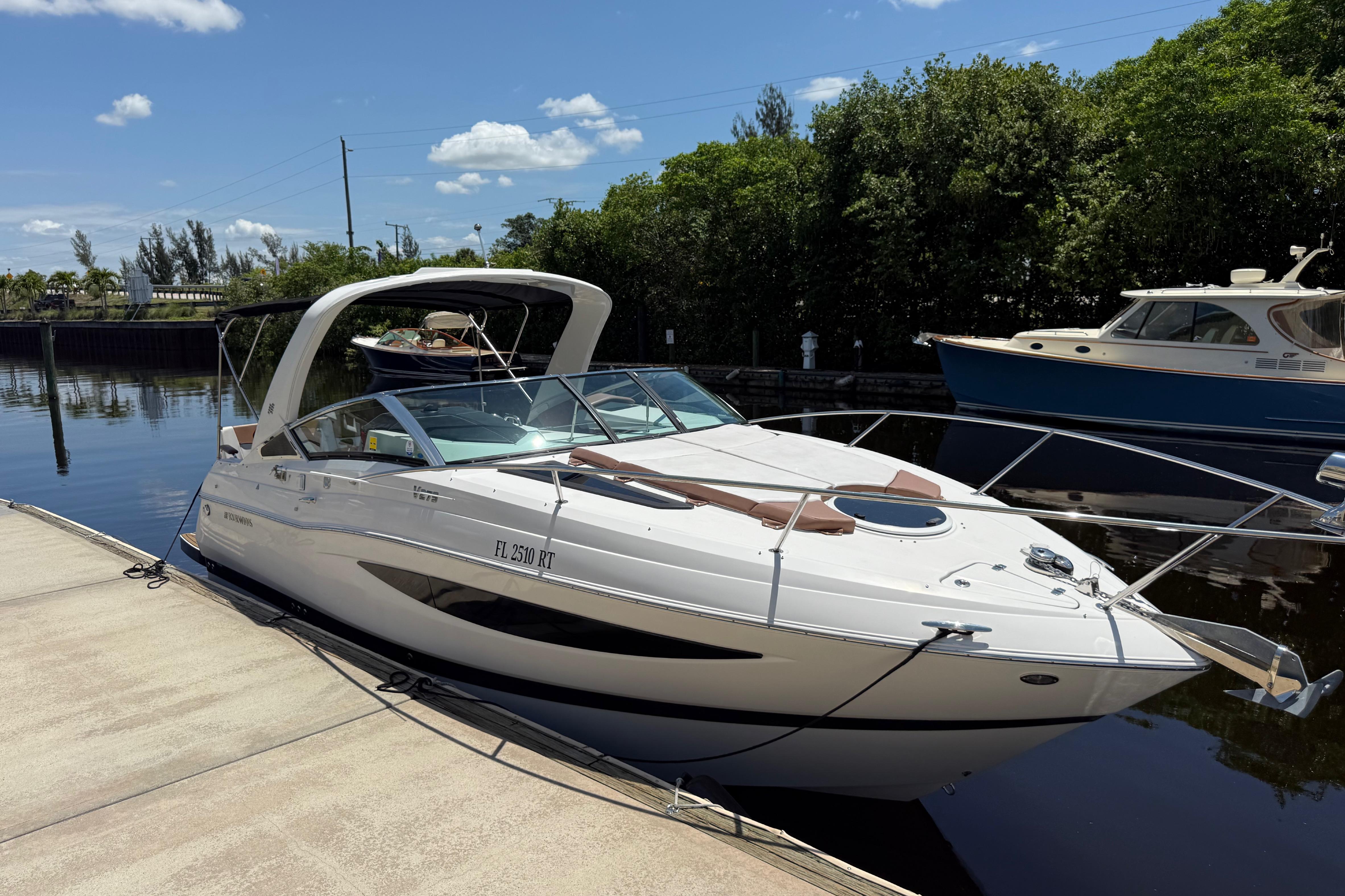 2017 Four Winns V275 boat docked on a sunny day, surrounded by lush greenery.