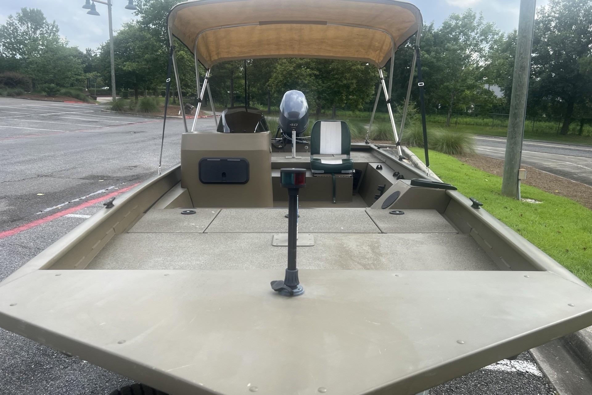 2016 G3 1756 SC boat with canopy in a parking lot, featuring a motor and seating.