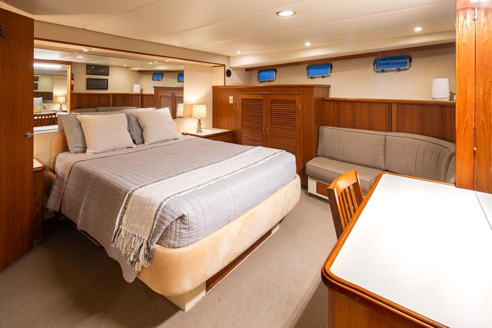 Luxurious bedroom interior of 1991 Tollycraft 57 Pilothouse Motor Yacht with cozy bed and seating.