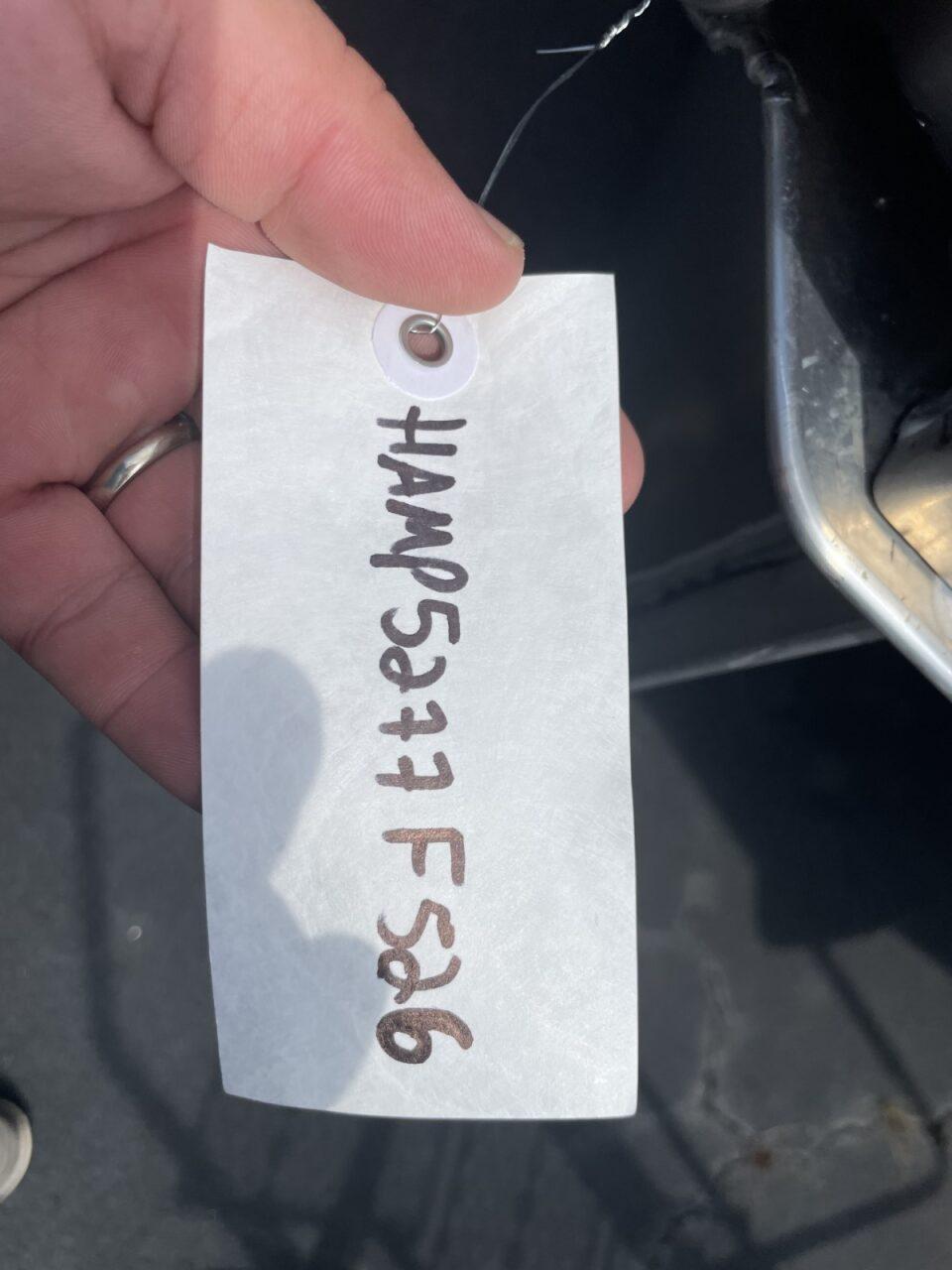 Hand holding a tag with handwritten code, near a Harris Cruiser 230, 2026 model.