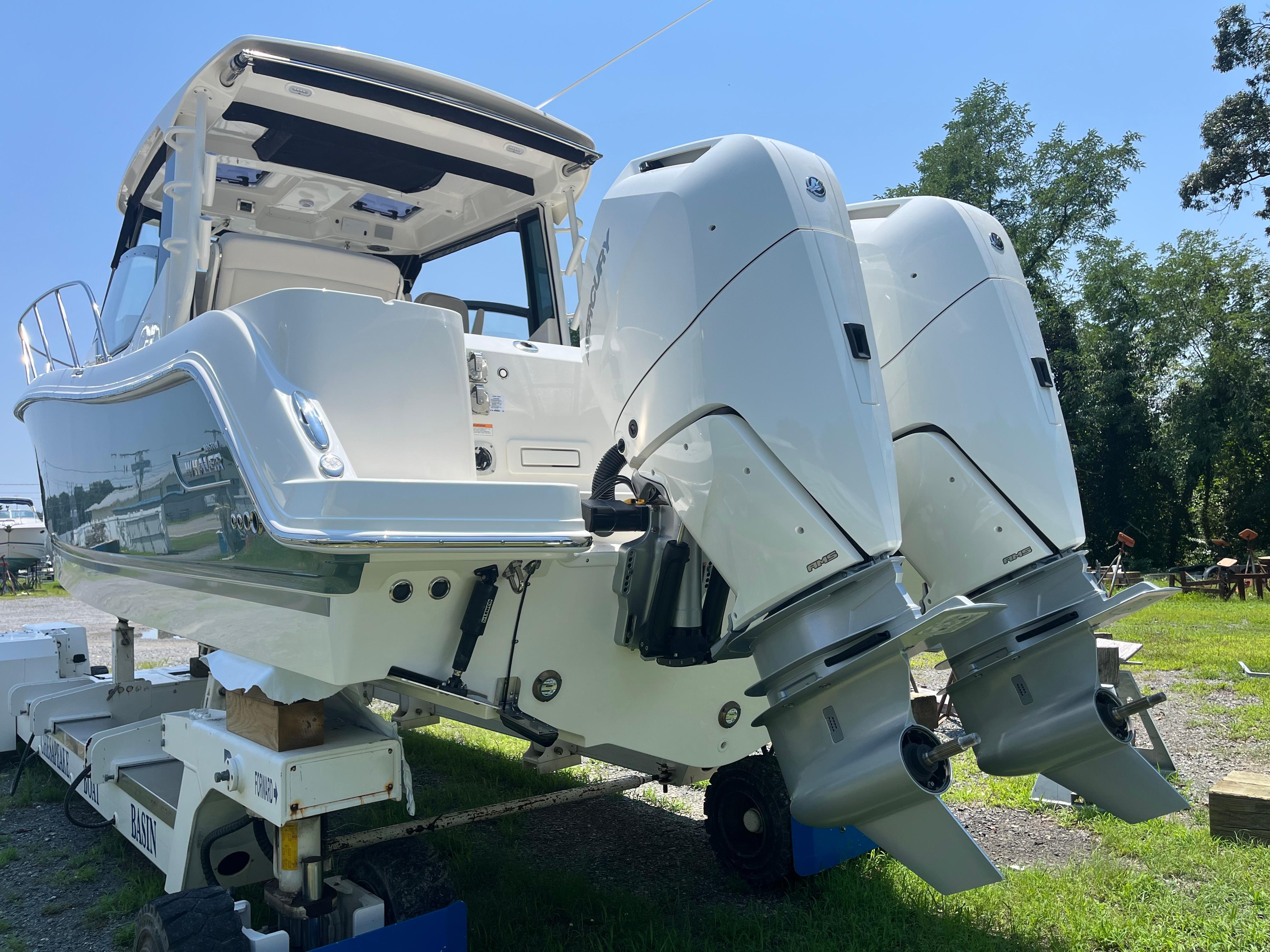 2025 Boston Whaler 325 Conquest with dual outboard engines on display outdoors.