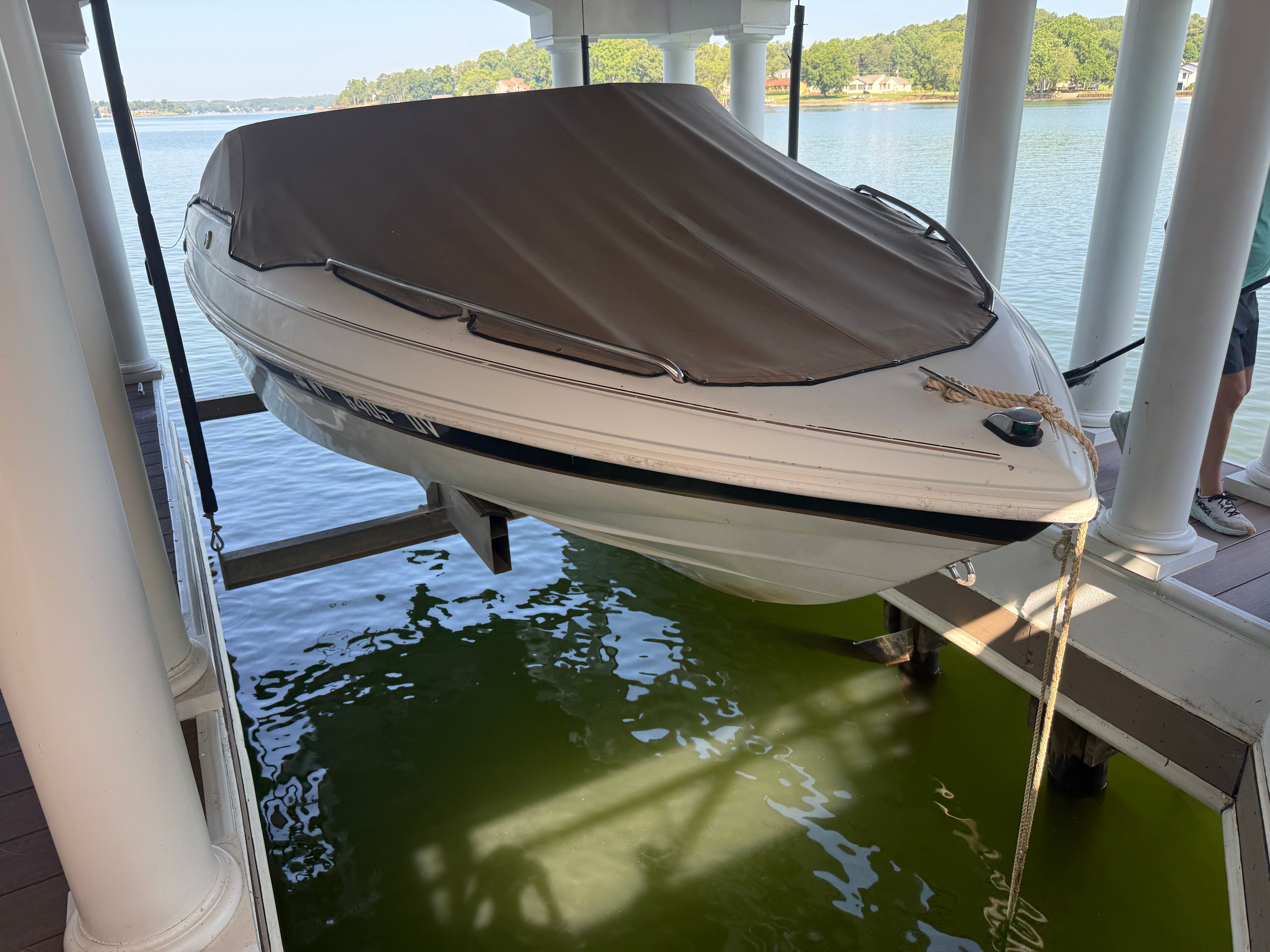 A 2000 Starcraft Next Star 19 boat on a lift above green water.