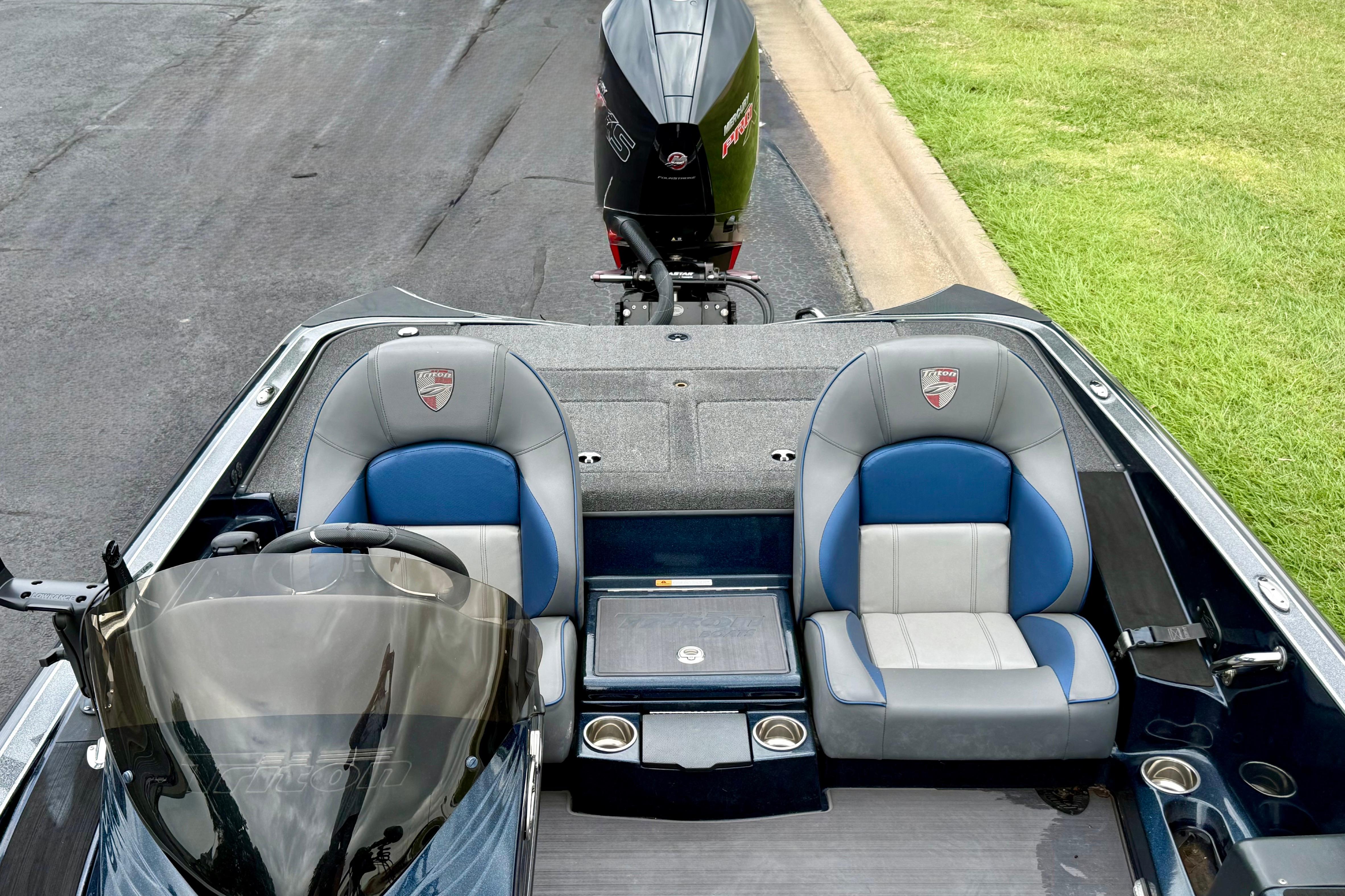 2023 Triton 18 TrX boat interior with dual seats and motor, parked on pavement.