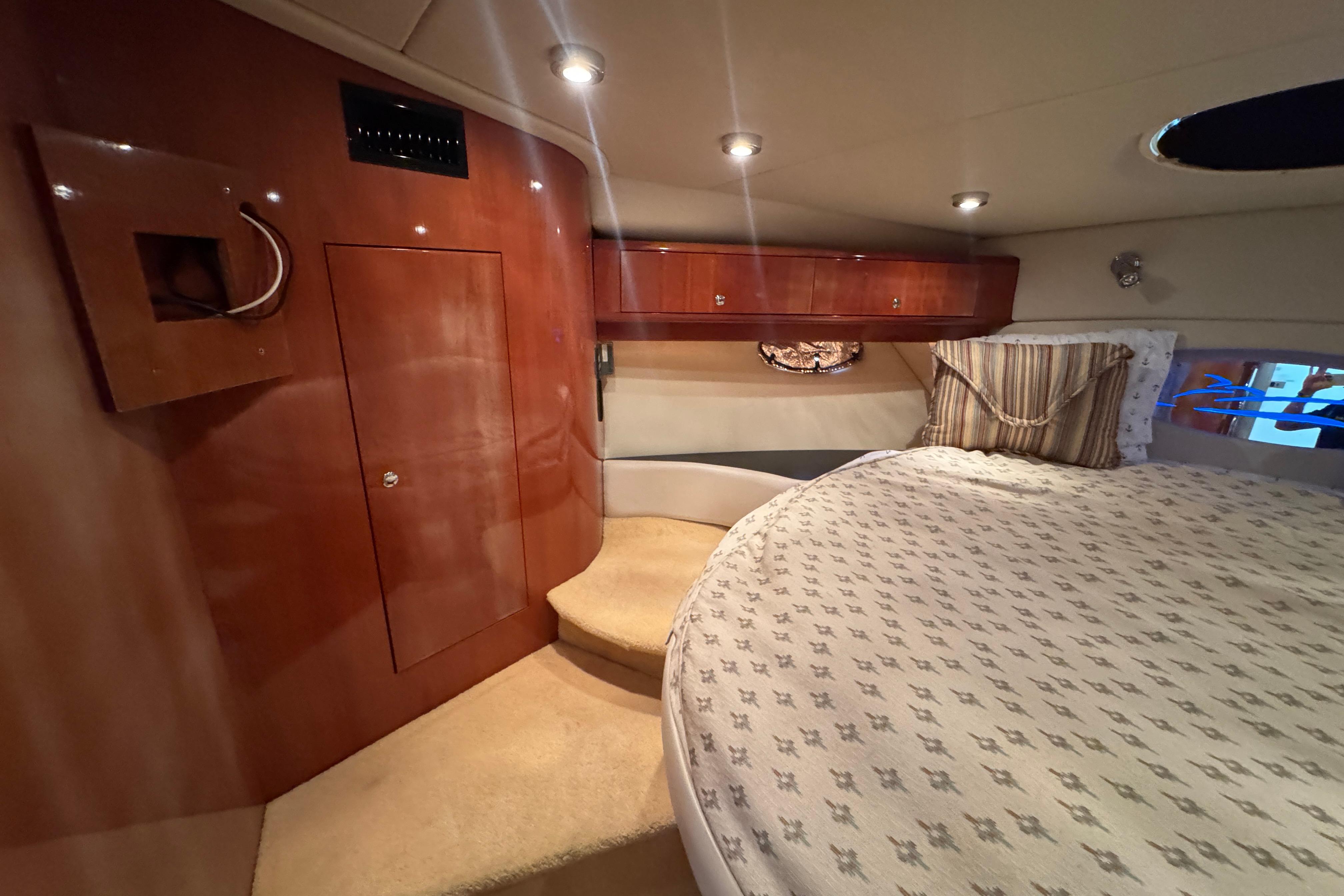 Luxurious cabin interior of 2005 Regal Commodore 4260 yacht with cozy bed and wooden cabinetry.