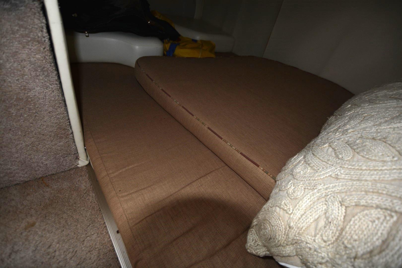 Interior cabin of 1999 Rinker 270 Fiesta Vee with brown cushions and a knitted pillow.