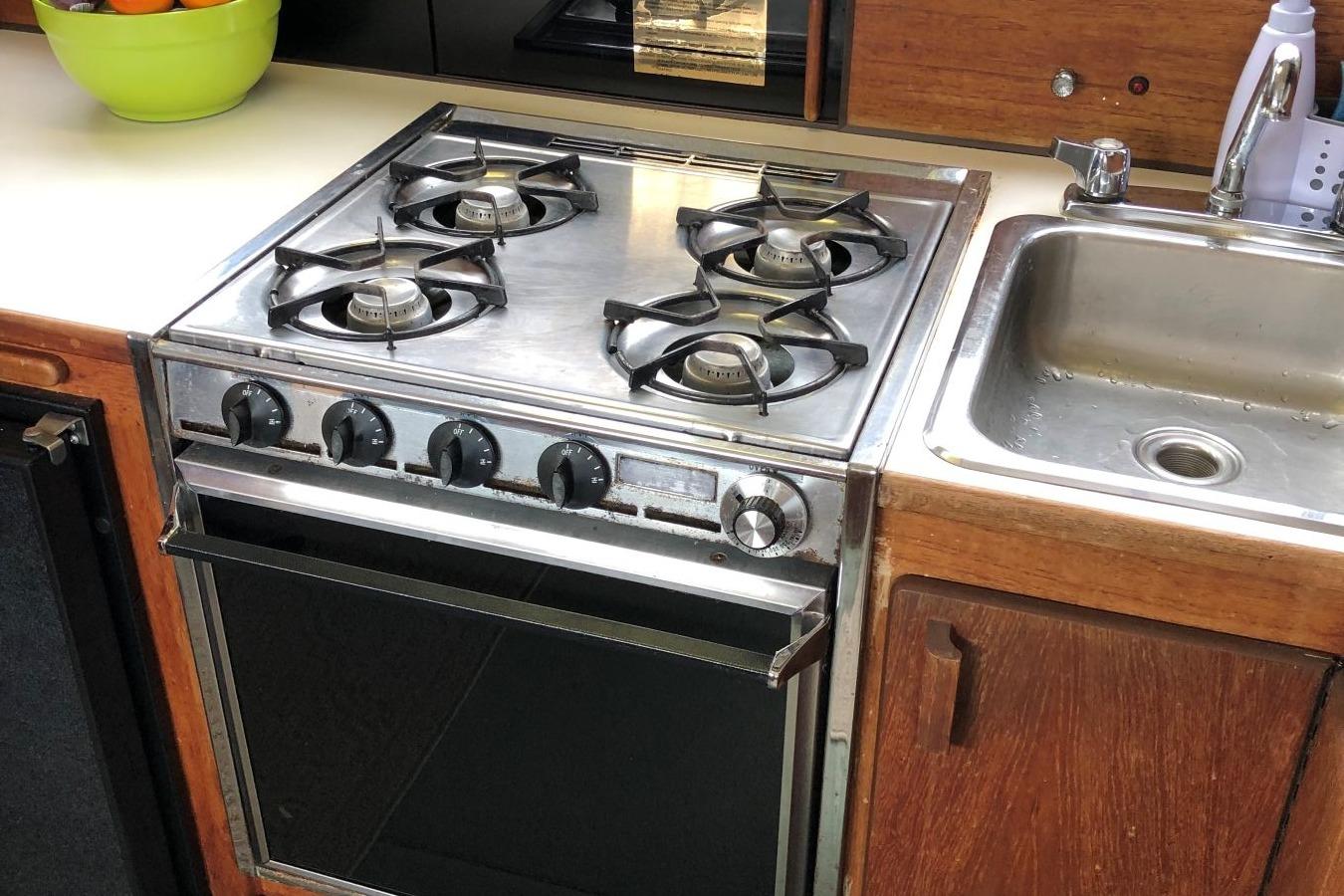 1988 Commander 30 Command Bridge kitchen with stove, sink, and wooden cabinetry.