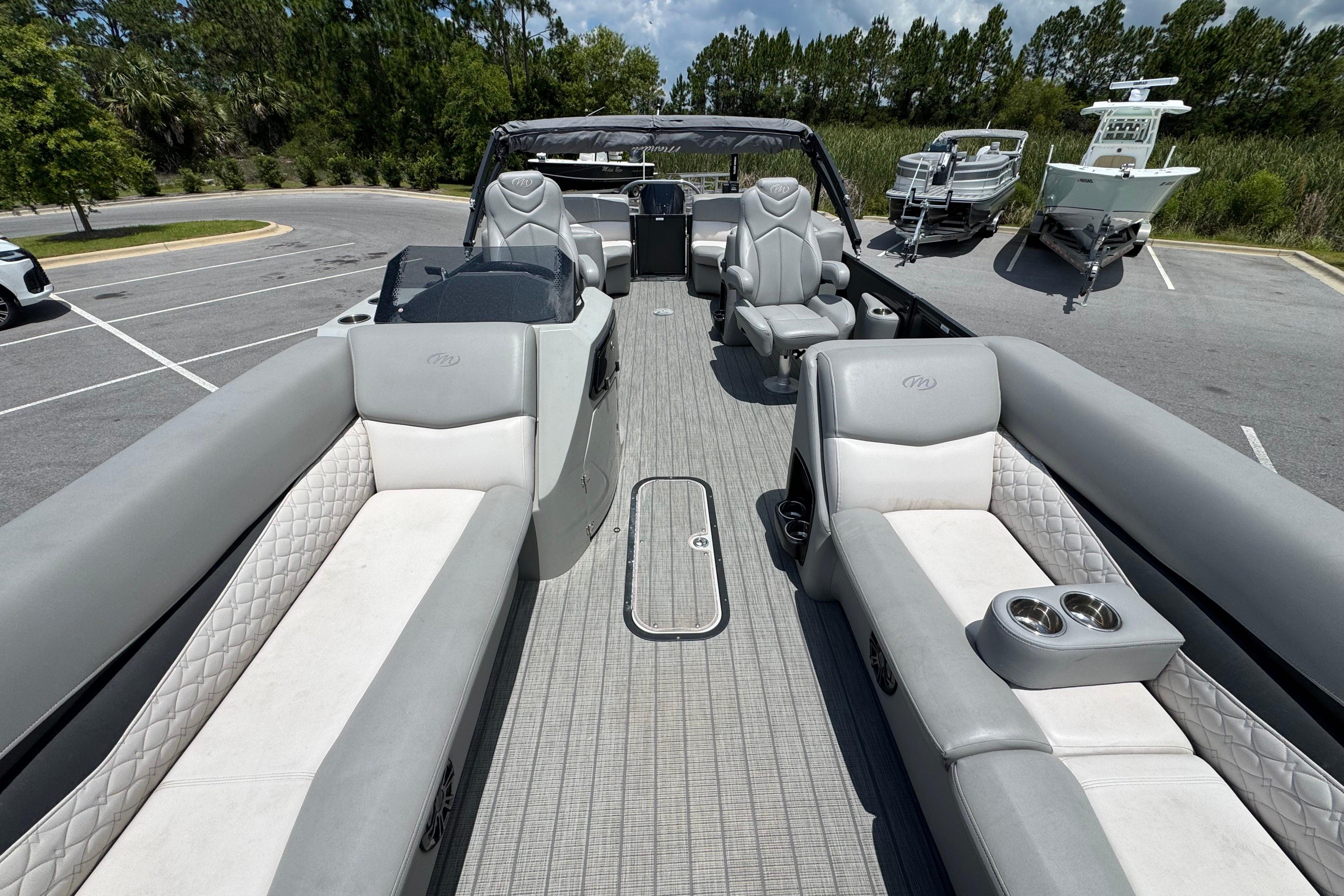 2022 Manitou 25 Encore pontoon boat with luxurious seating in a parking lot.