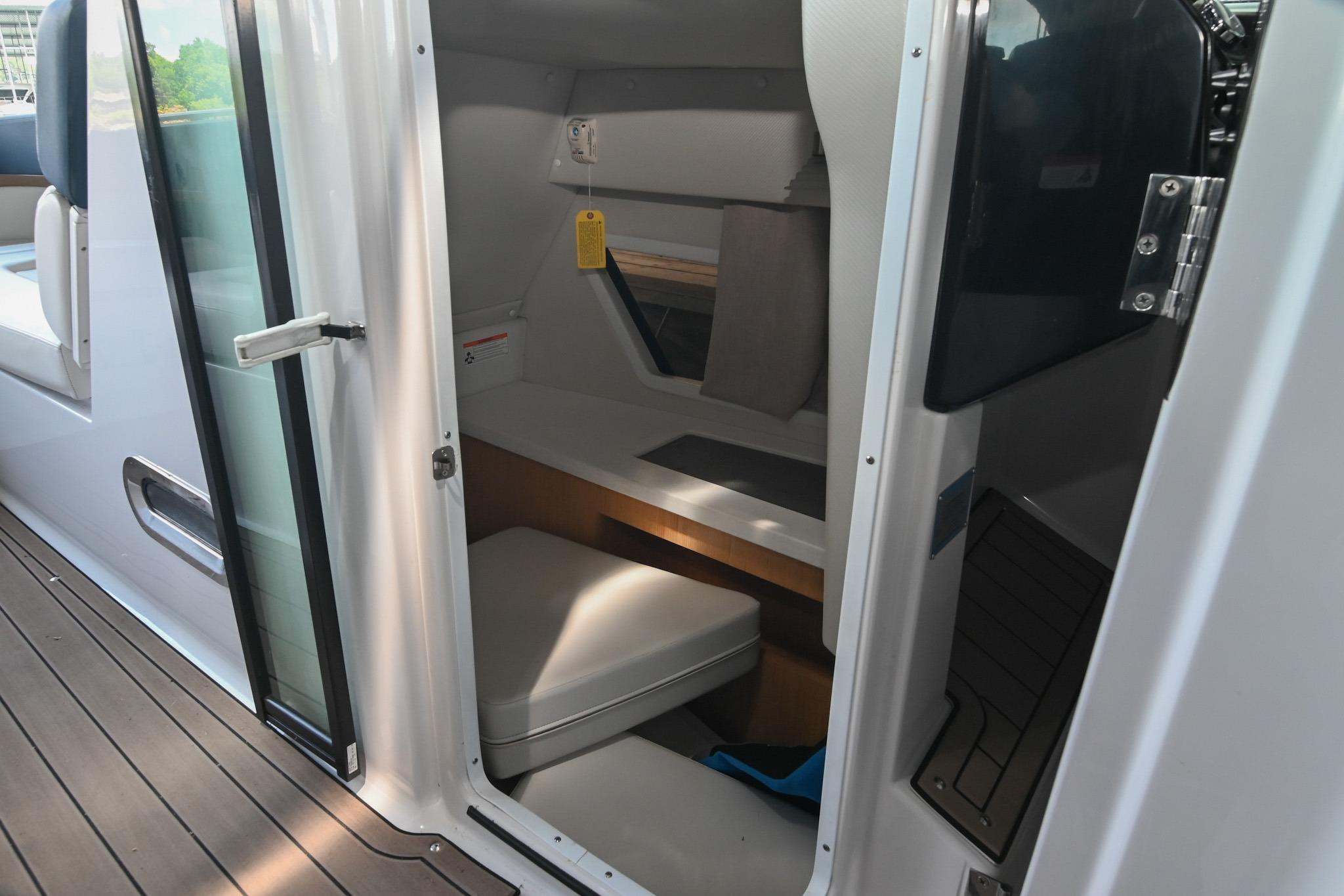 2014 Four Winns H290 cabin interior with open door, showcasing seating and storage.