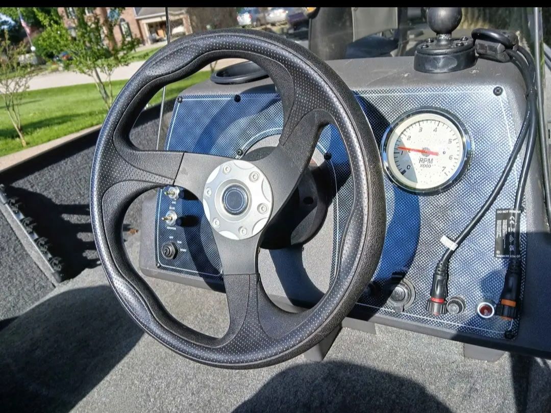 Close-up of a boat steering wheel and dashboard with a tachometer.
