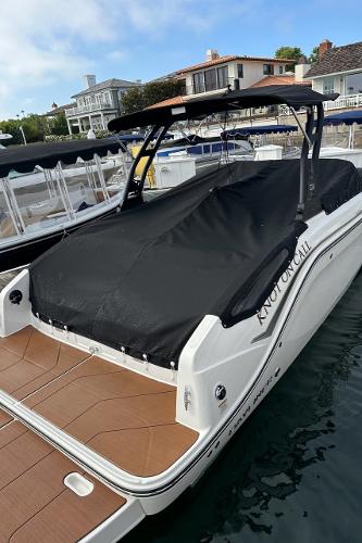 2024 Bayliner DX 2250 boat docked, covered with black tarp, in a marina setting.