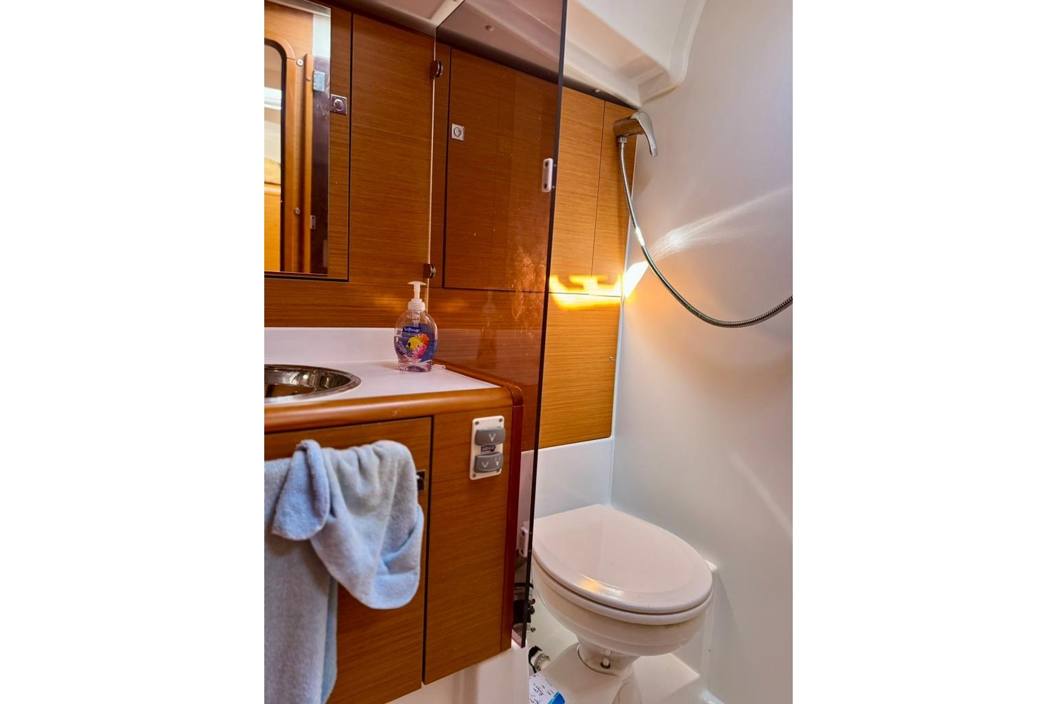 Bathroom interior of 2017 Jeanneau Sun Odyssey 449 yacht, featuring wooden cabinetry and modern fixtures.
