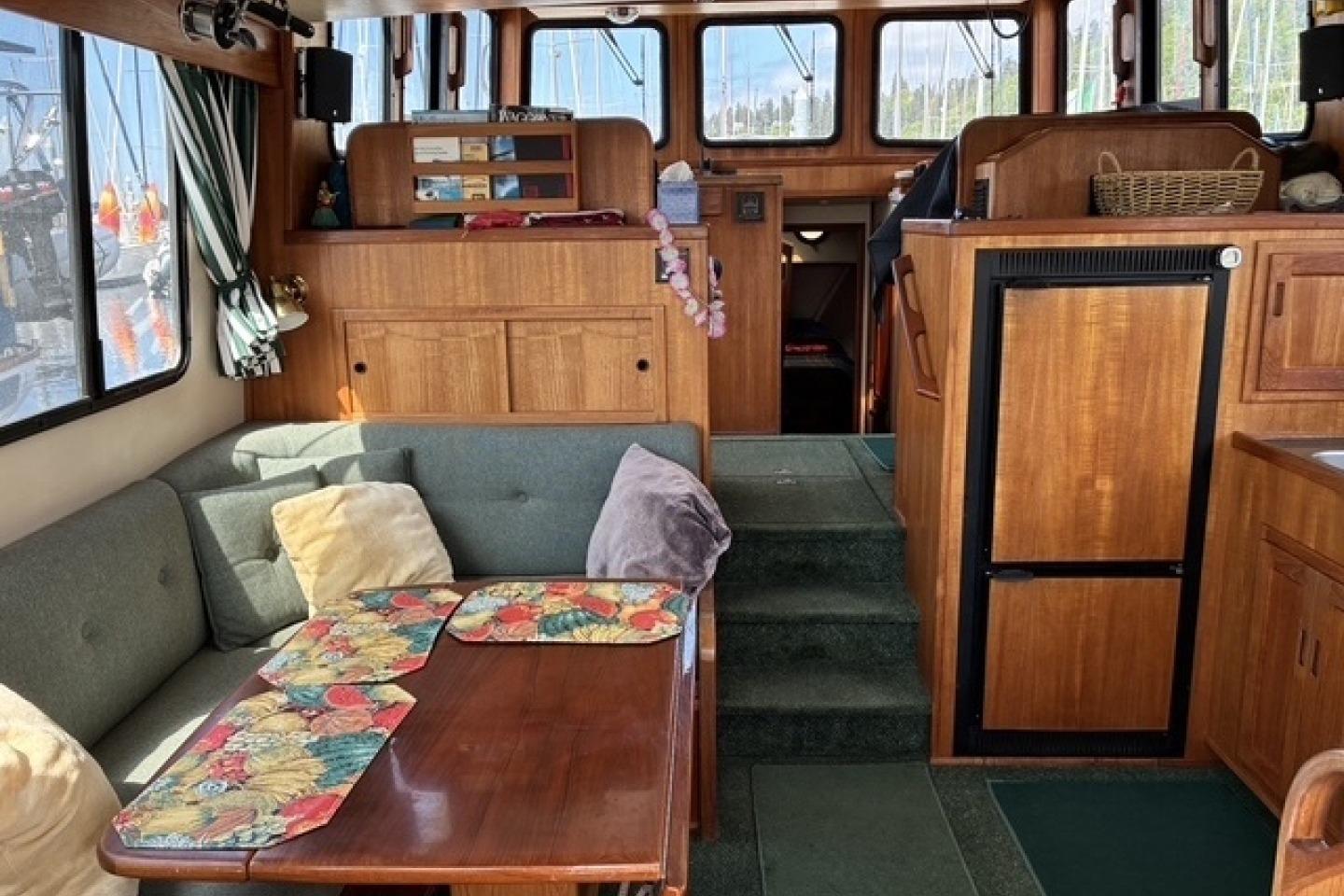 Interior of a 2000 Nordic Tug 37, featuring cozy seating and wooden cabinetry.