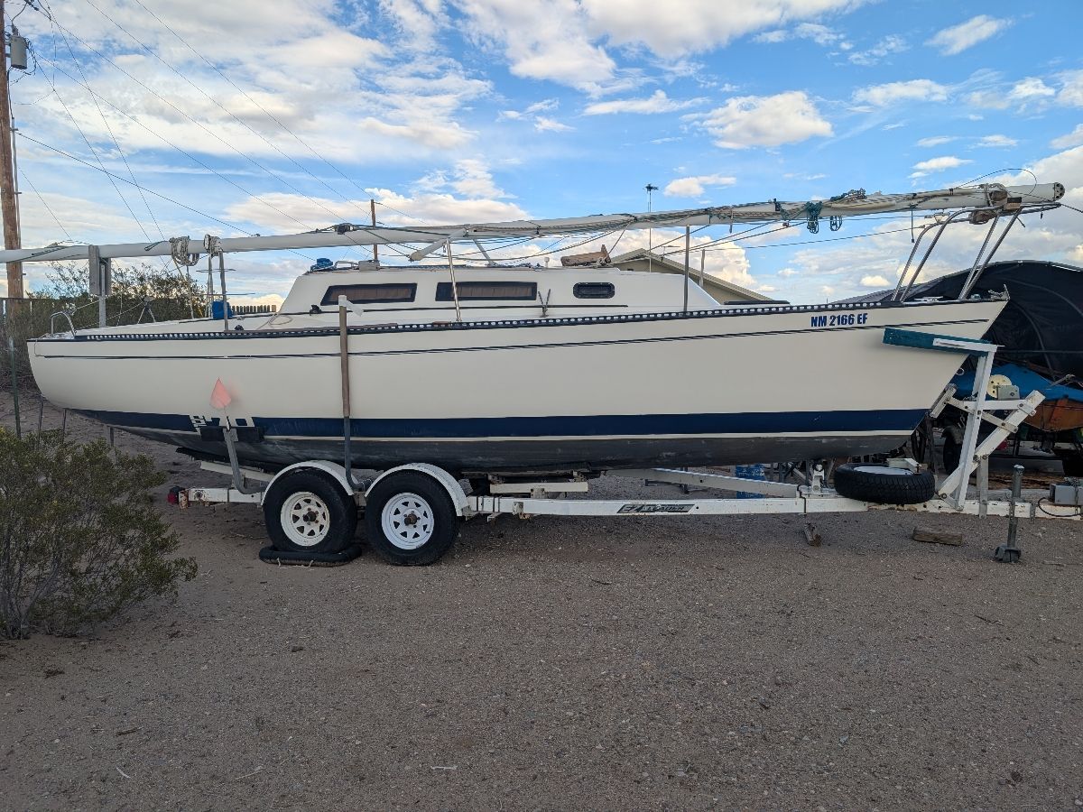 A white sailboat on a trailer, surrounded by desert and sky.