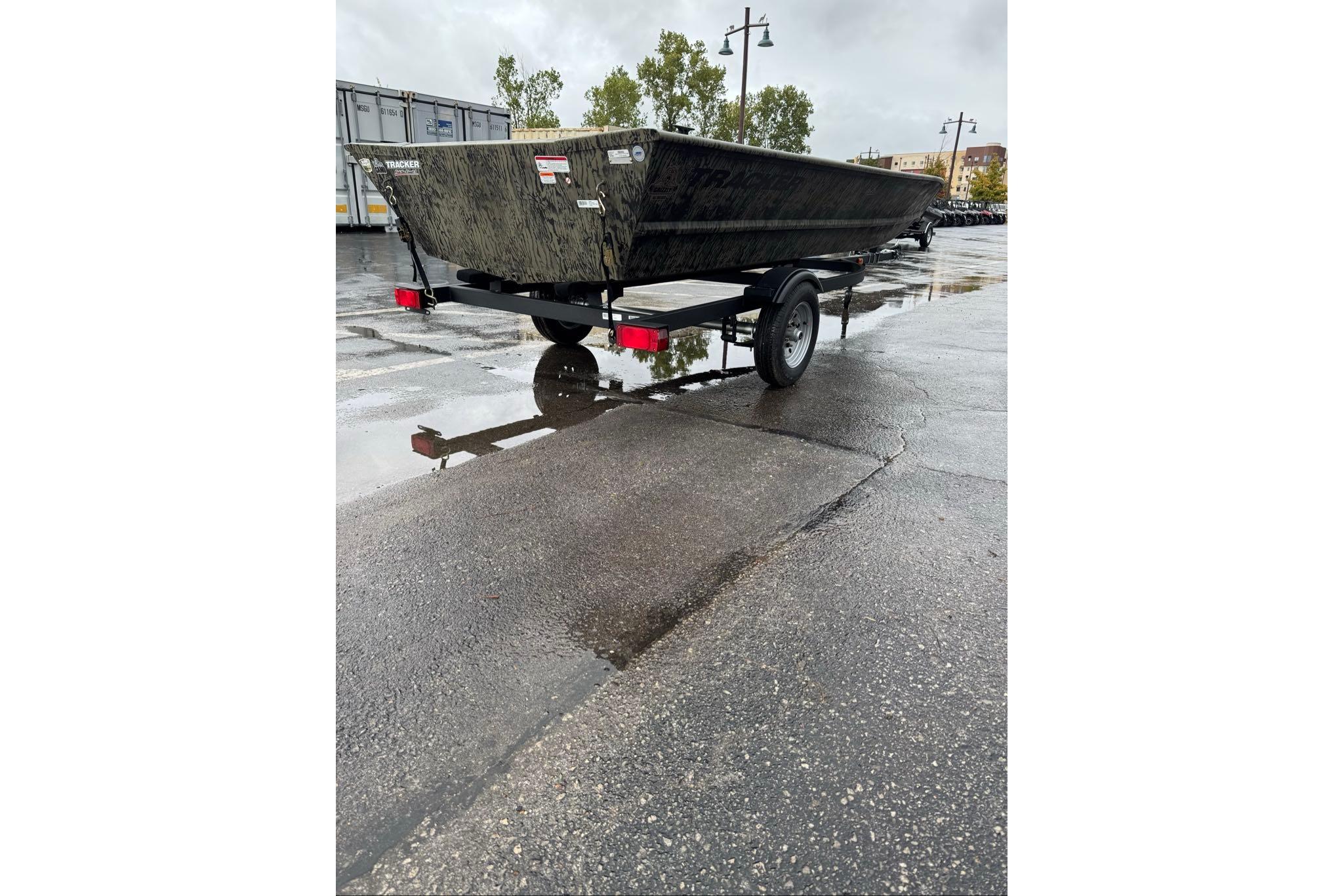 2026 Tracker Grizzly 1648 Utility boat on trailer in wet parking lot.