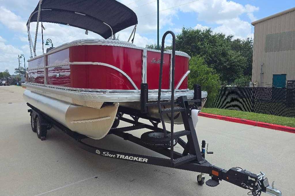 2026 Sun Tracker Party Barge 20 DLX pontoon boat on trailer, red exterior, parked outdoors.