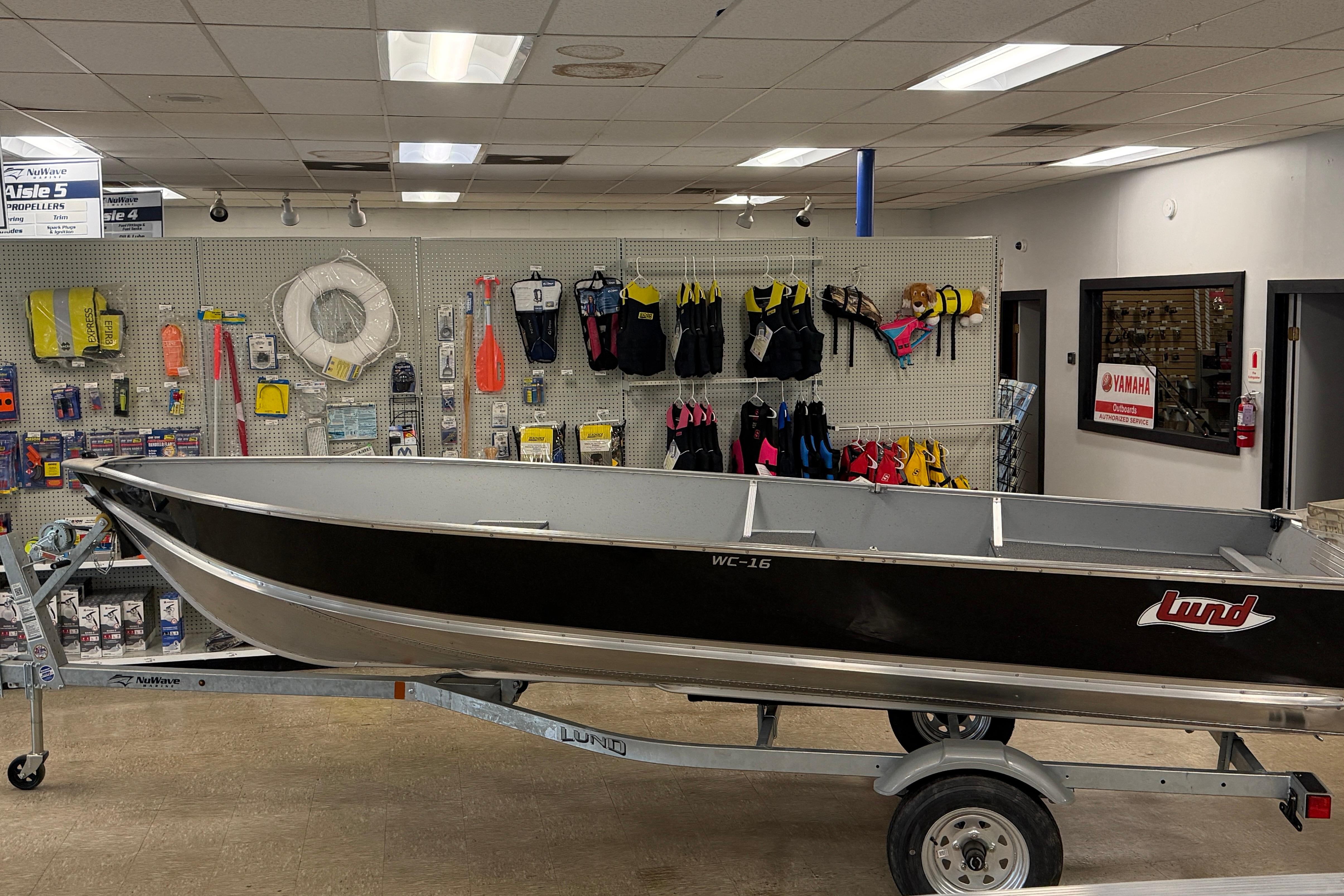 2027 Lund WC 16 boat displayed in a store with boating accessories.