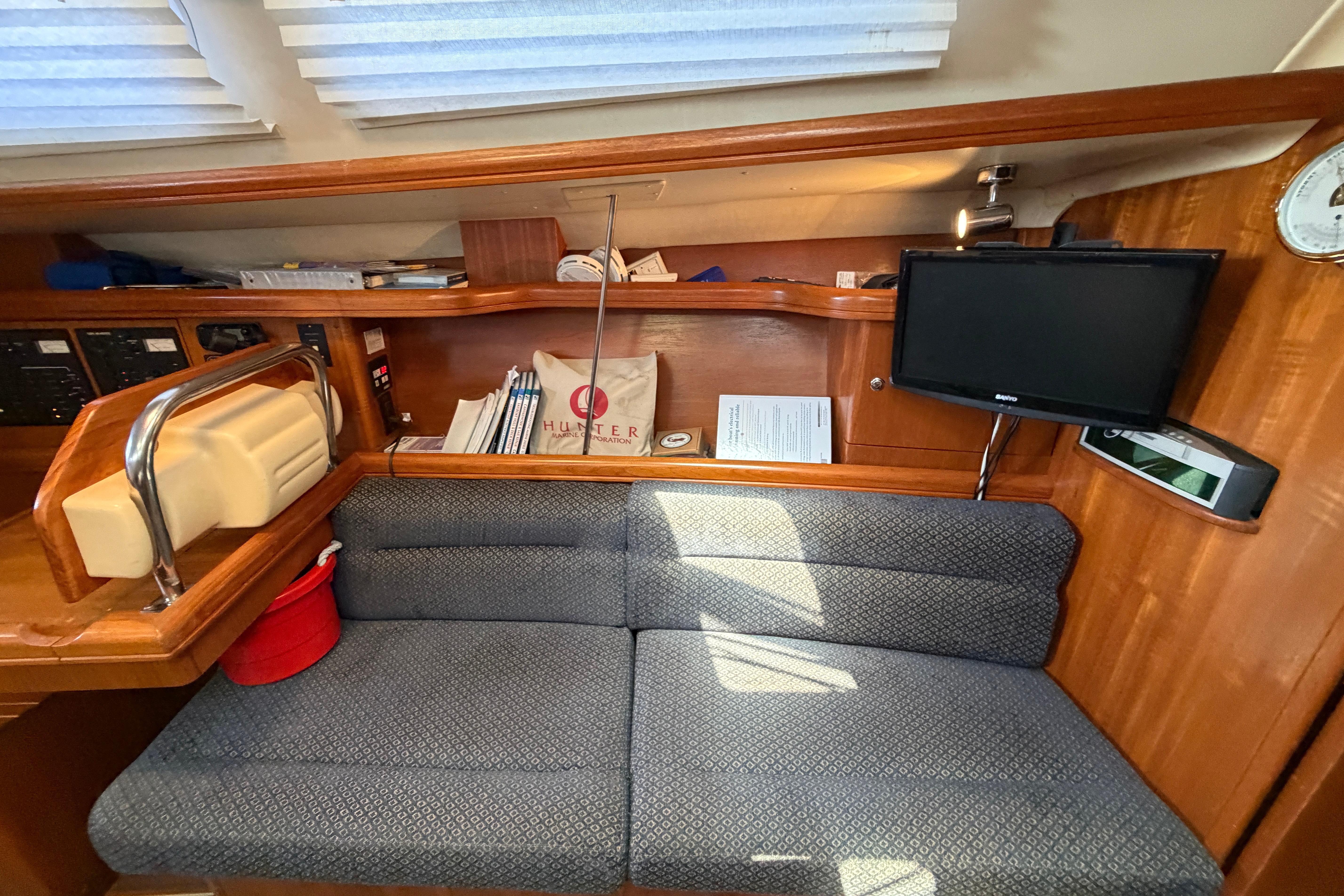 Interior of a 2005 Hunter 38 sailboat with a cozy seating area and mounted TV.