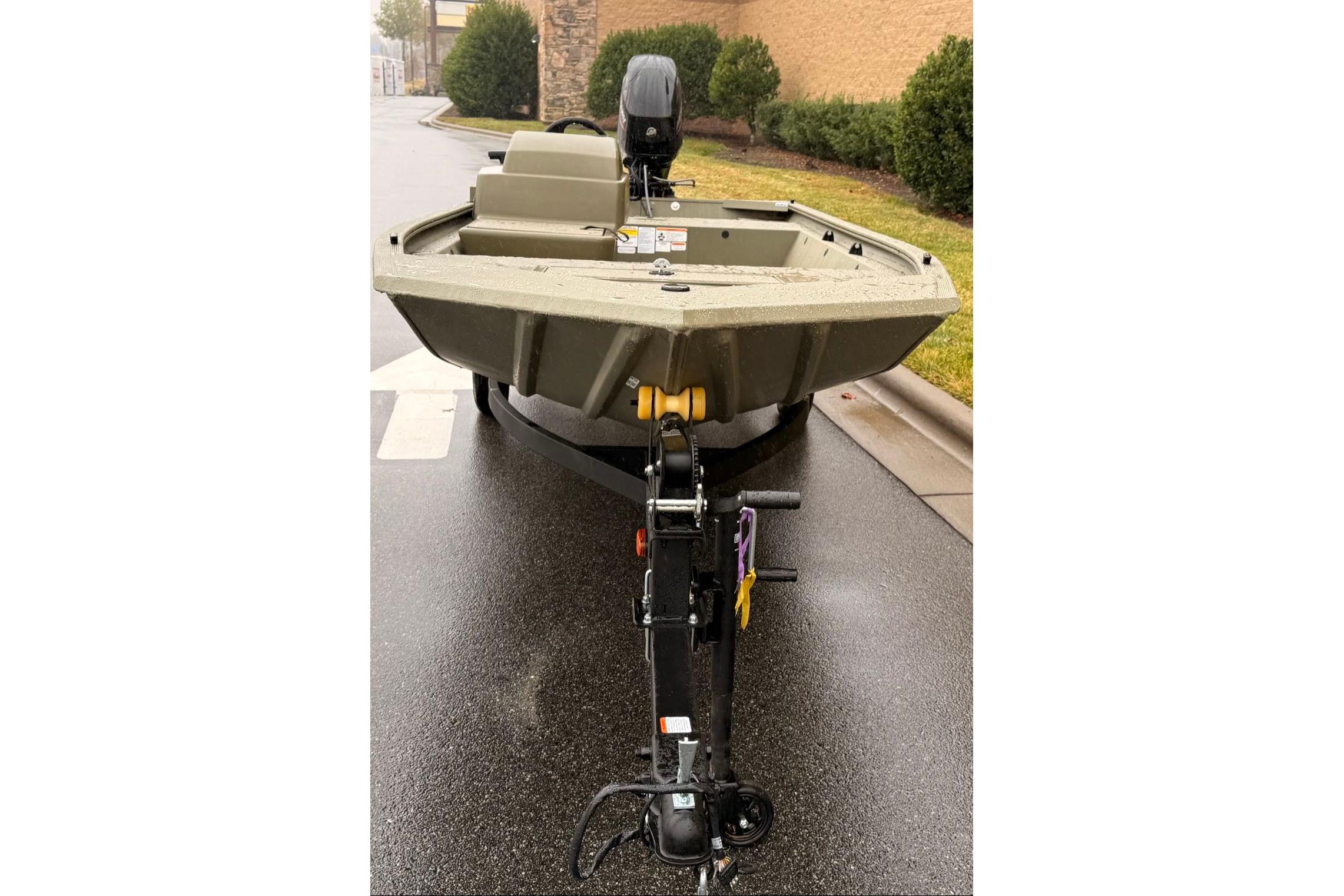2026 Tracker Grizzly 1648 SC boat on trailer, parked on wet pavement.