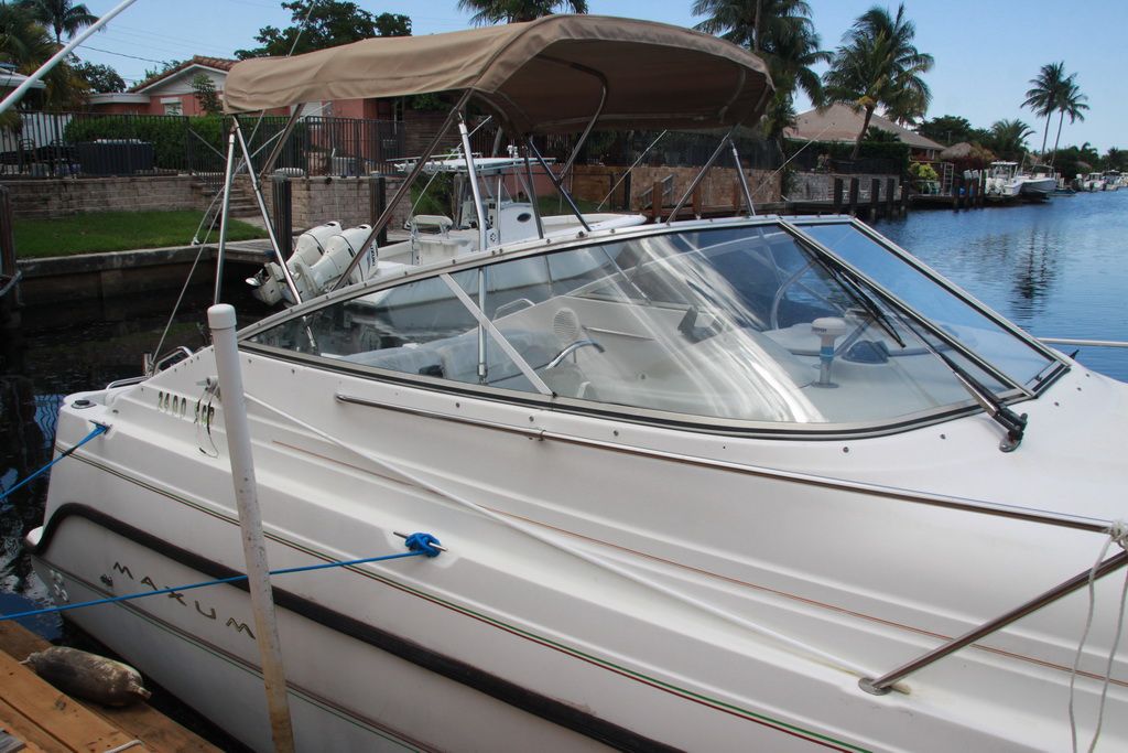 1999 Maxum 2400 Mercruiser boat docked with palm trees in background.