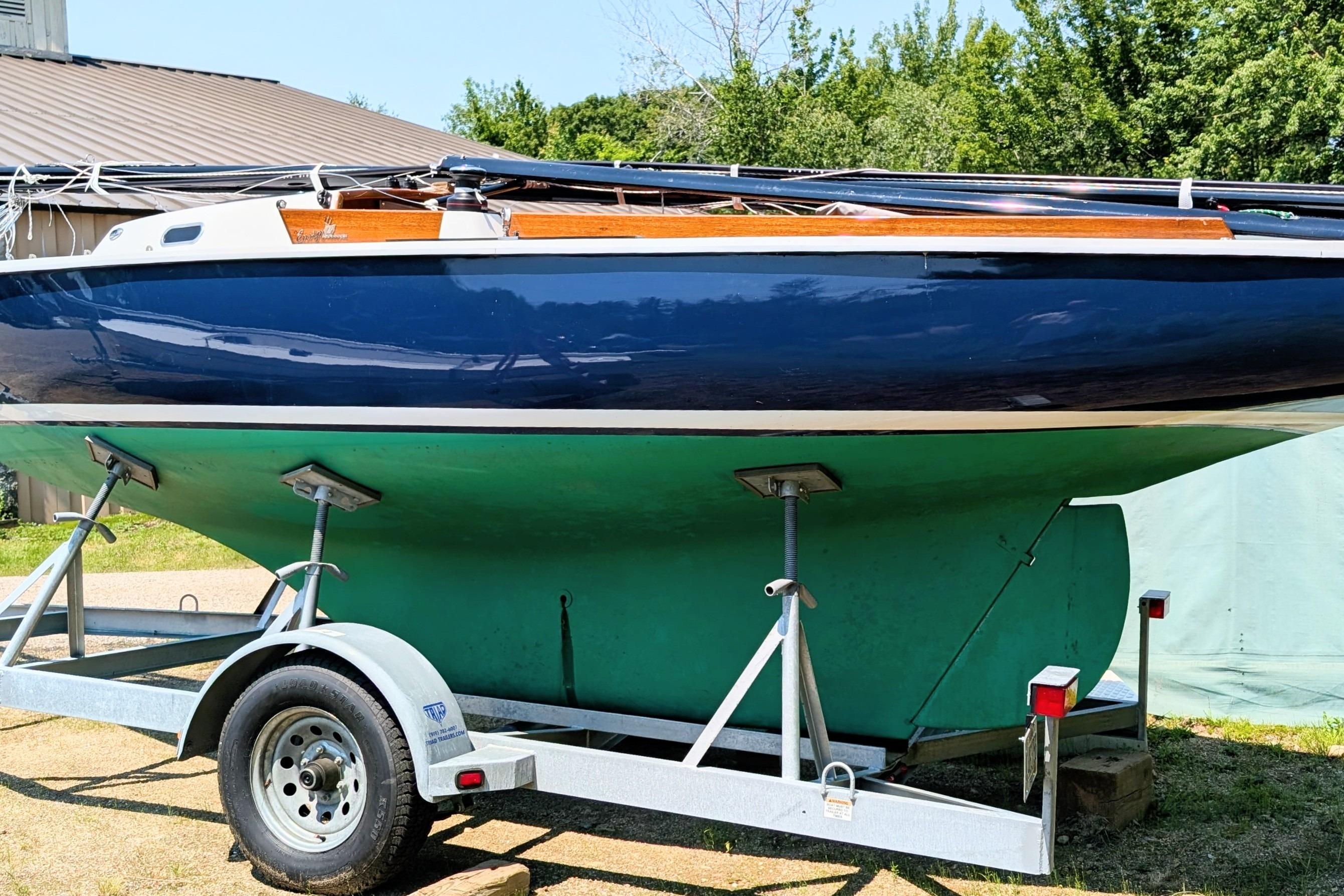 1965 Pearson Ensign sailboat on trailer, blue hull, green bottom, parked outdoors.