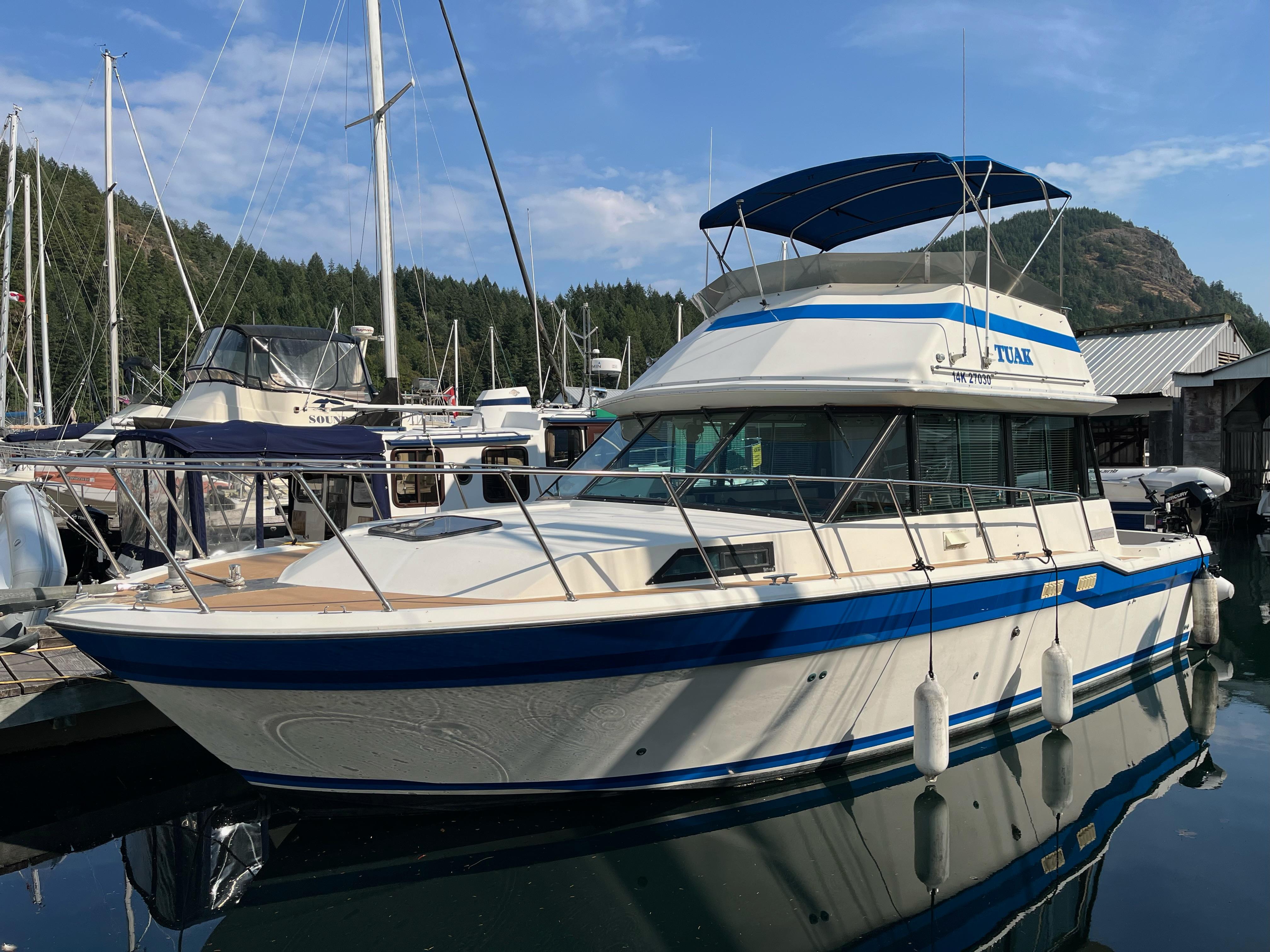 1976 Fiberform Executive 3300 boat docked in a marina, featuring blue and white design.