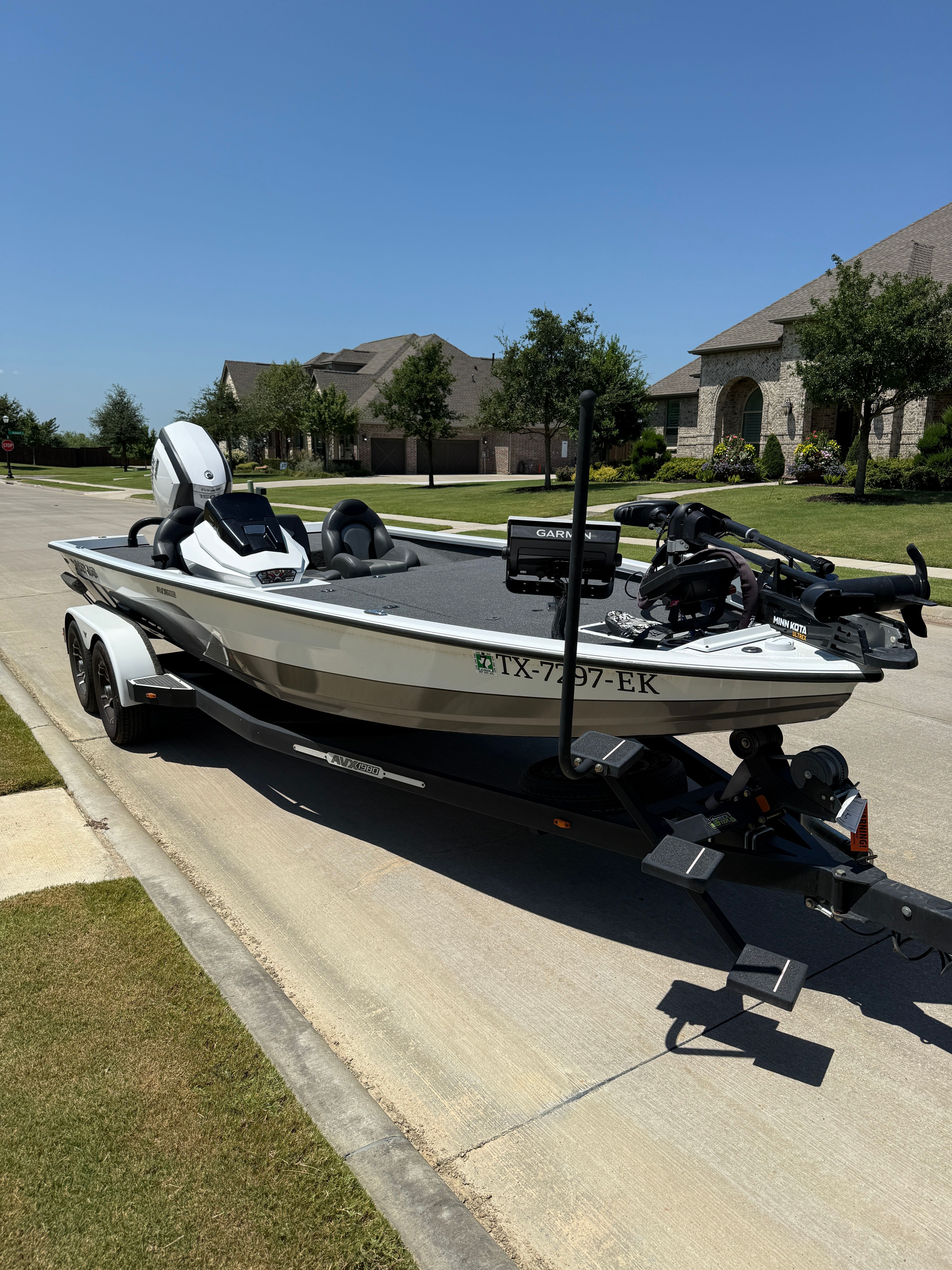 A 2019 Vexus AVX1980 boat on a trailer, parked on a residential street with modern houses.