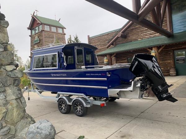 2023 Spartan 220 Maximus Pro boat on a trailer outside a rustic building.