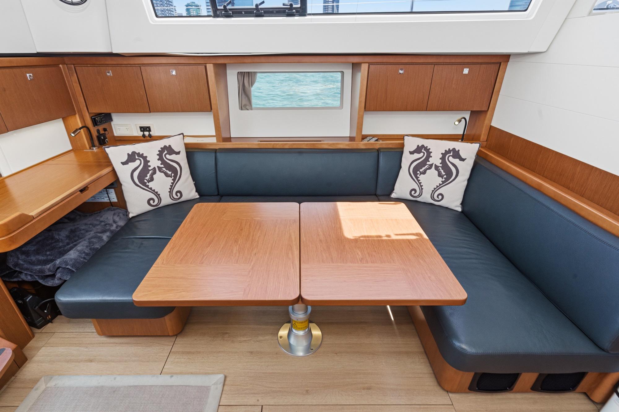 Interior of 2017 Beneteau Sense 50 yacht with cozy seating and seahorse-themed pillows.