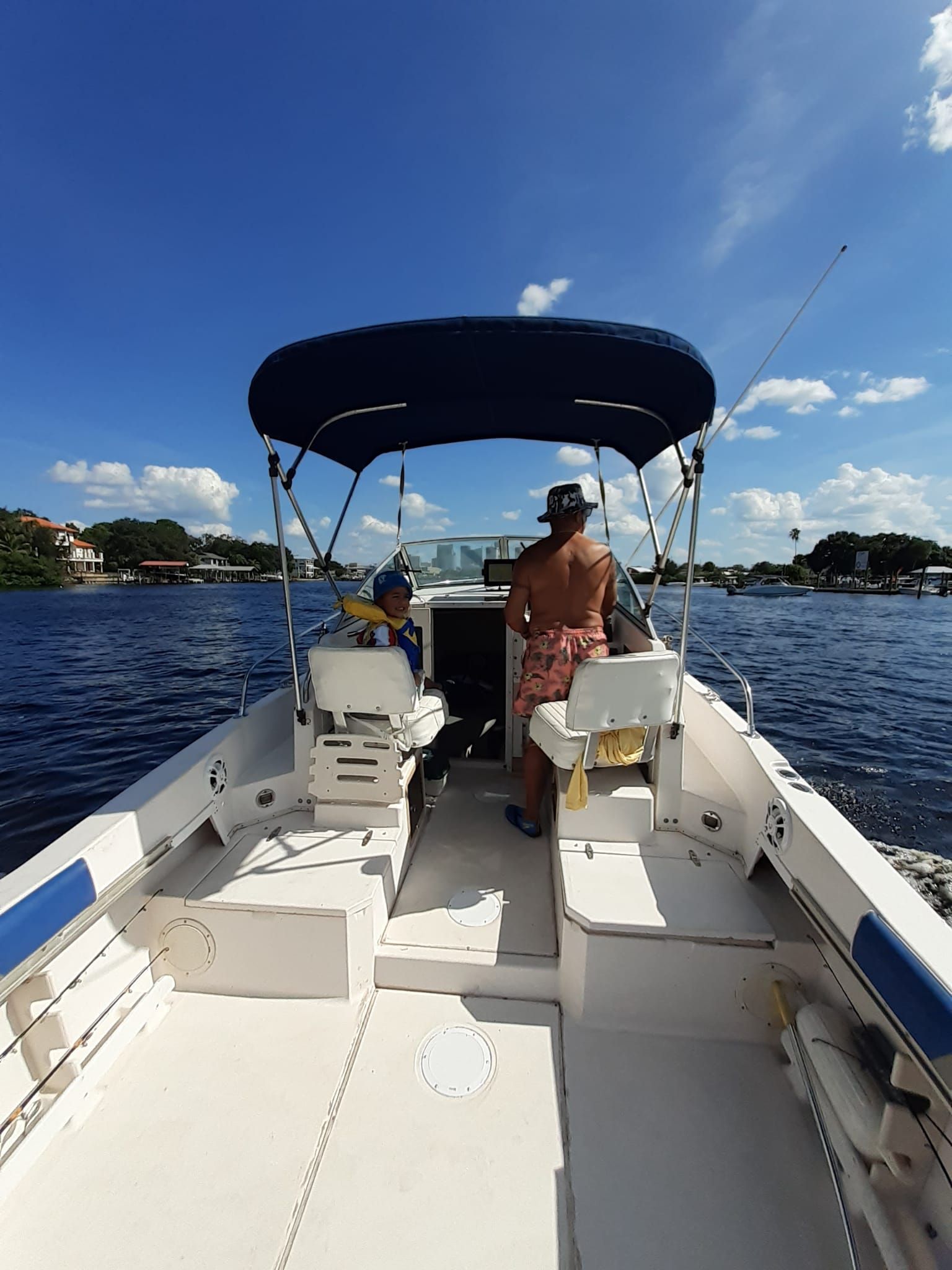 A 1995 Grady-White Explorer 24 on the water. Two people sit under a blue sunshade.