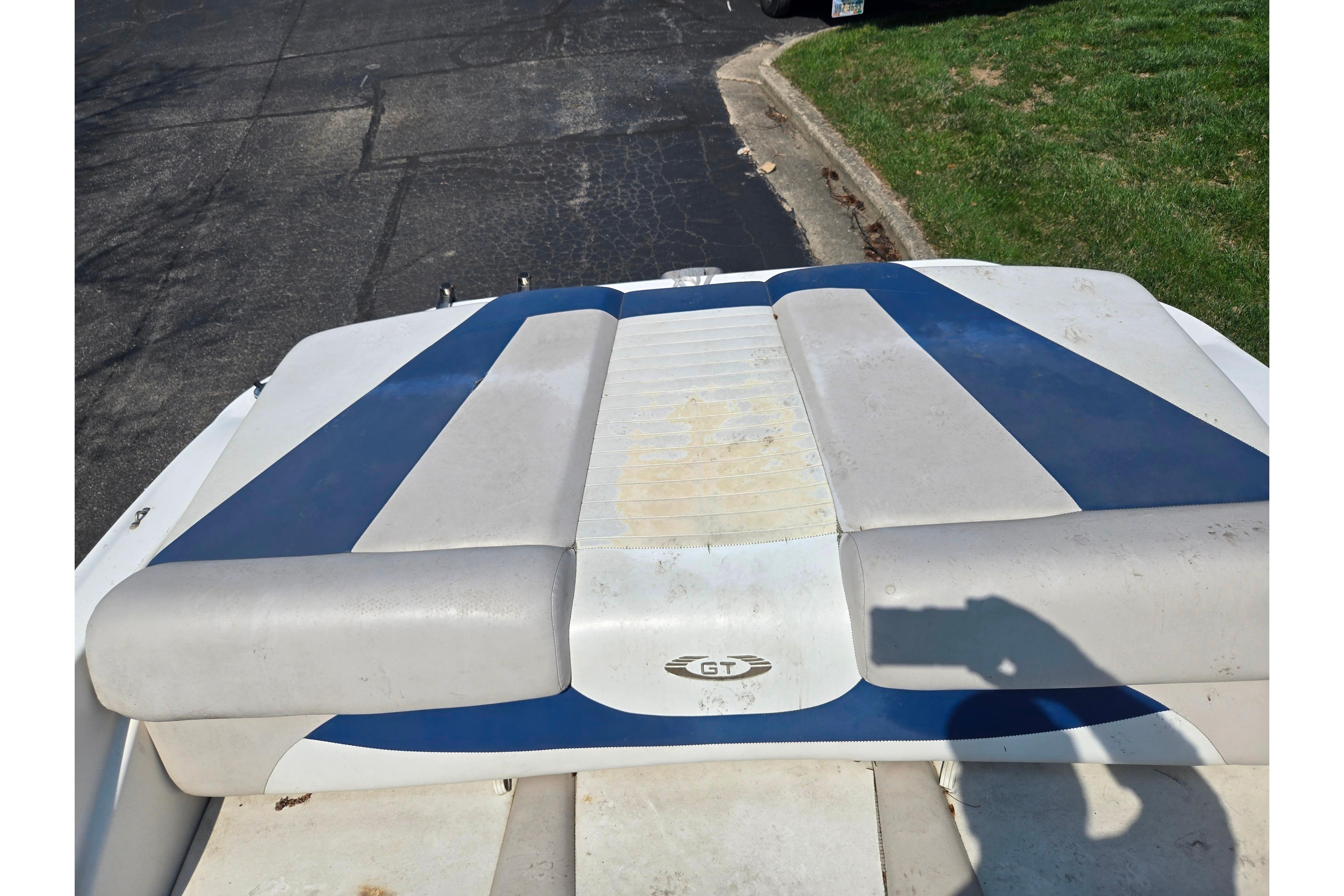 2007 Glastron GT 185 boat with blue and white upholstery, parked on pavement.
