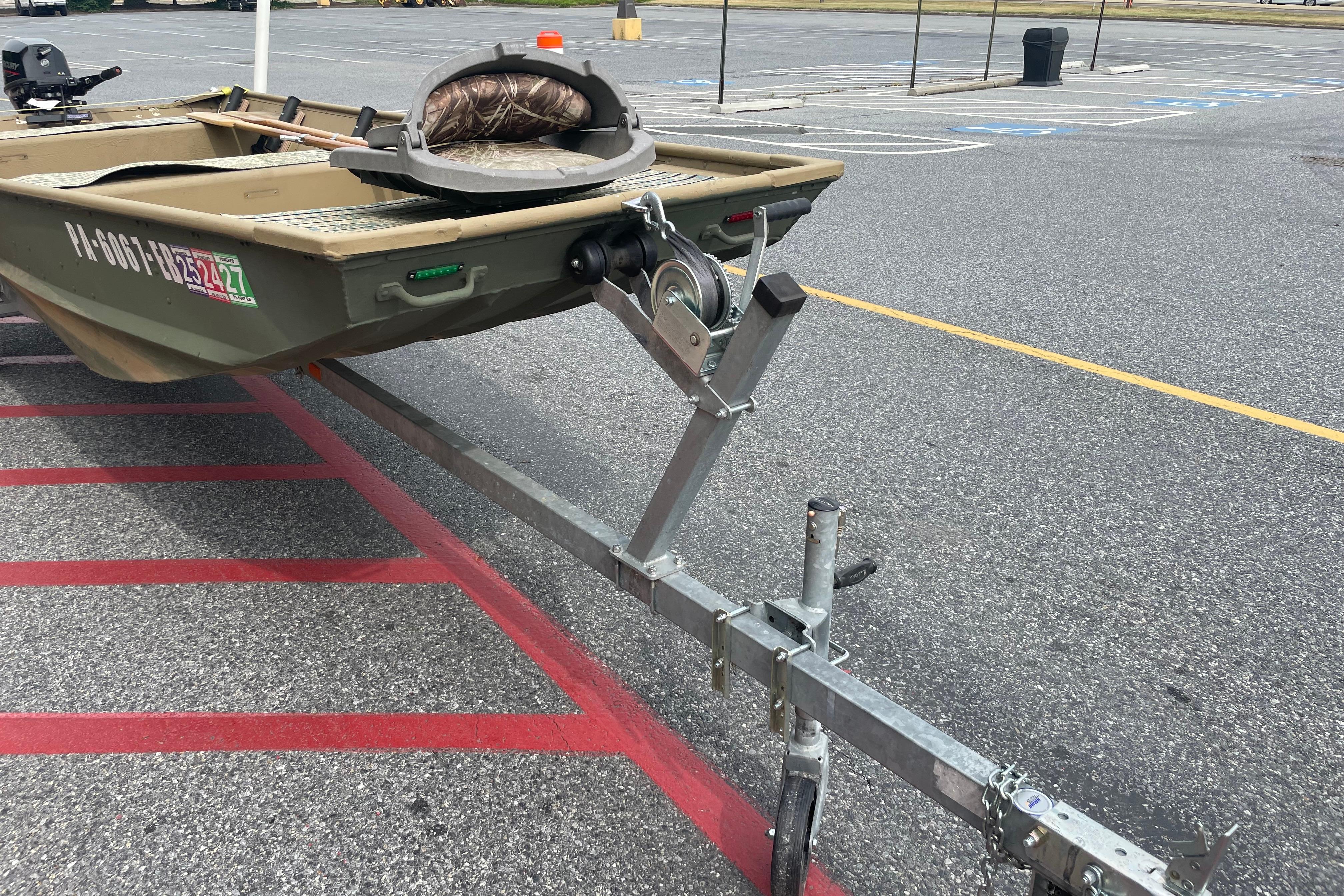1986 Landau 1664 Jon boat on trailer in parking lot, featuring camouflage seat.