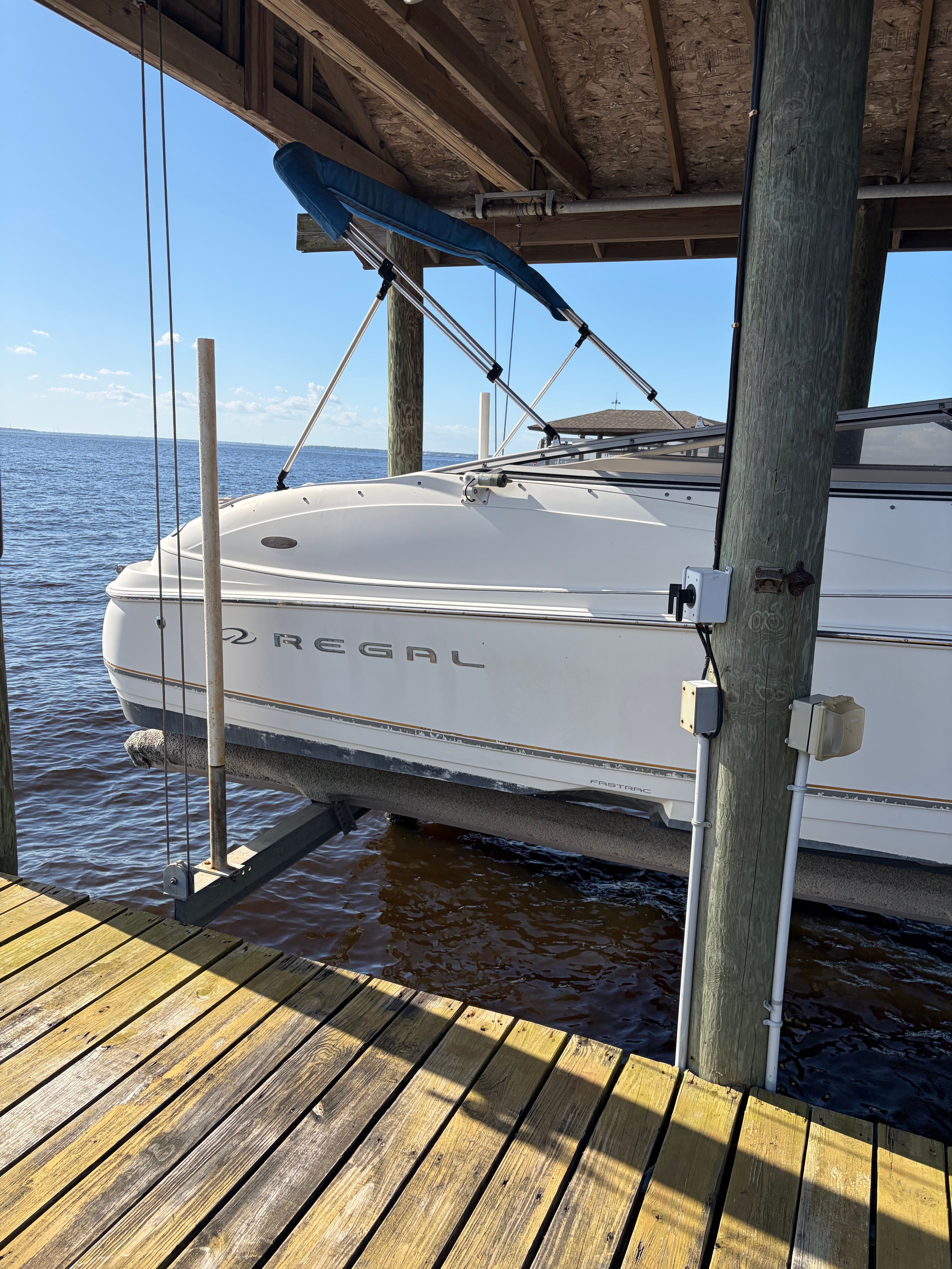 A 2002 Regal boat is suspended at a dock above the water.