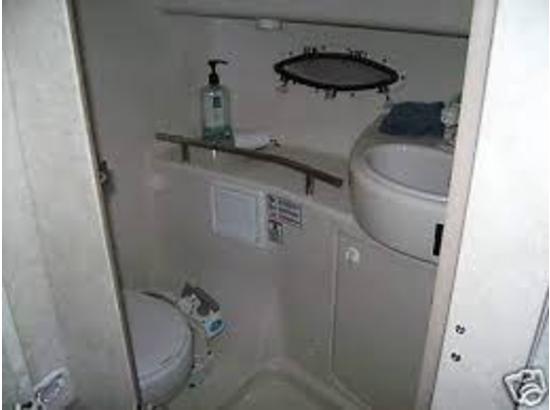 Compact bathroom in a 2000 Bayliner 3055 Ciera Sunbridge boat with toilet and sink.