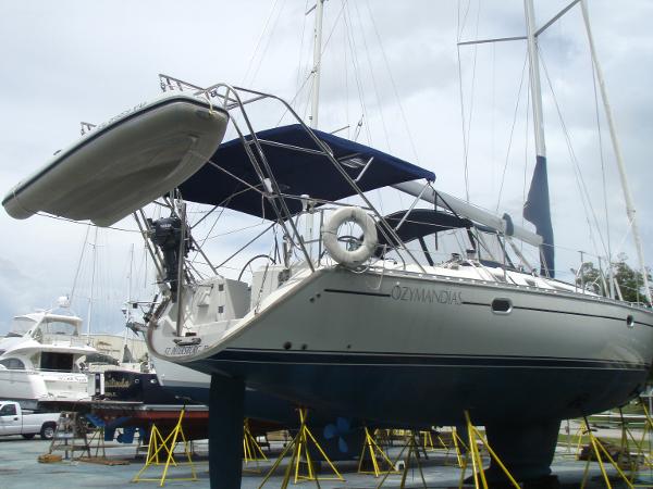 2001 Jeanneau 45.2 sailboat on stands, with blue canopy and dinghy, in a marina.