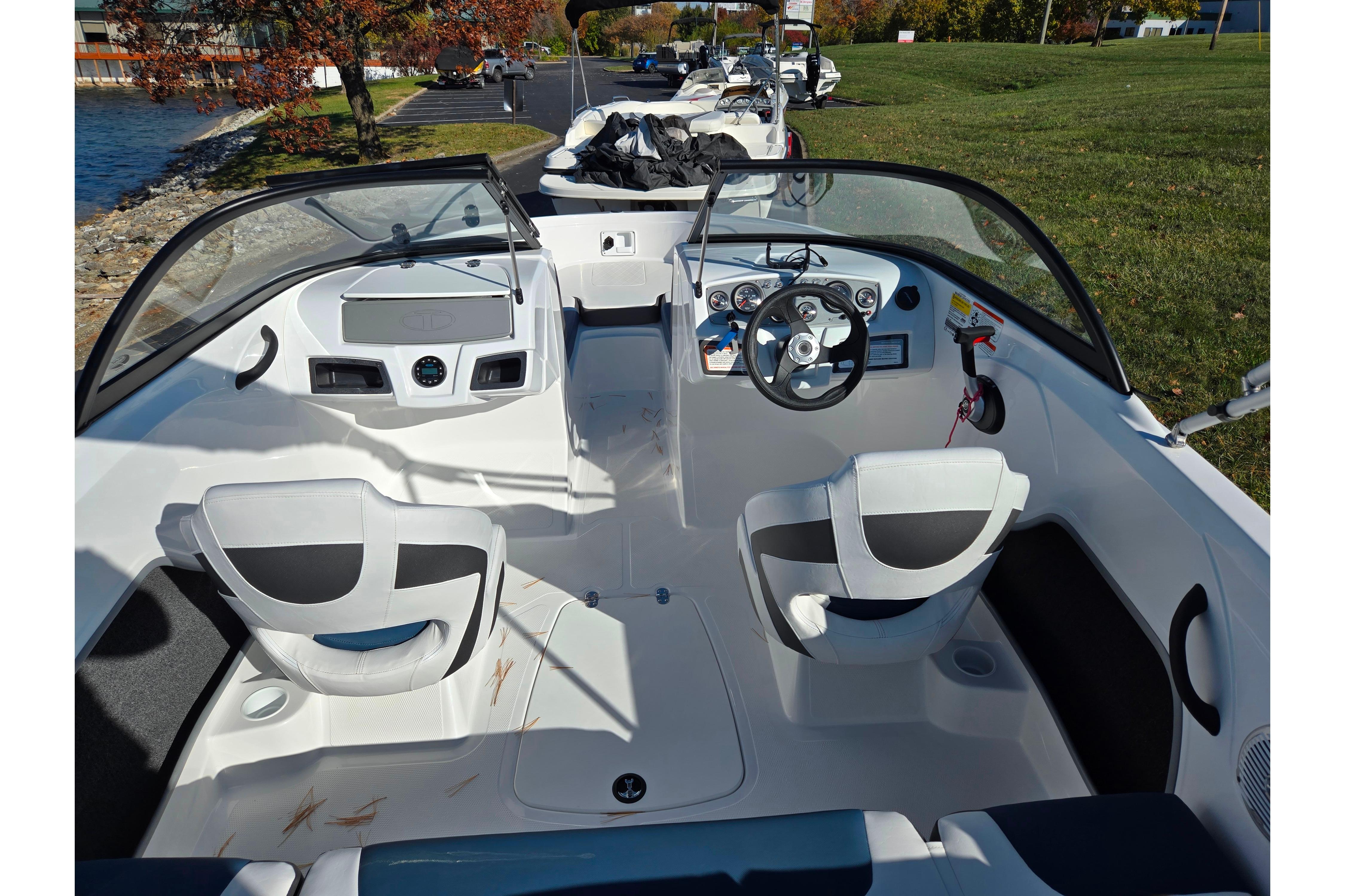 2023 Tahoe 185 S boat interior with steering wheel and seating, docked by a grassy area.