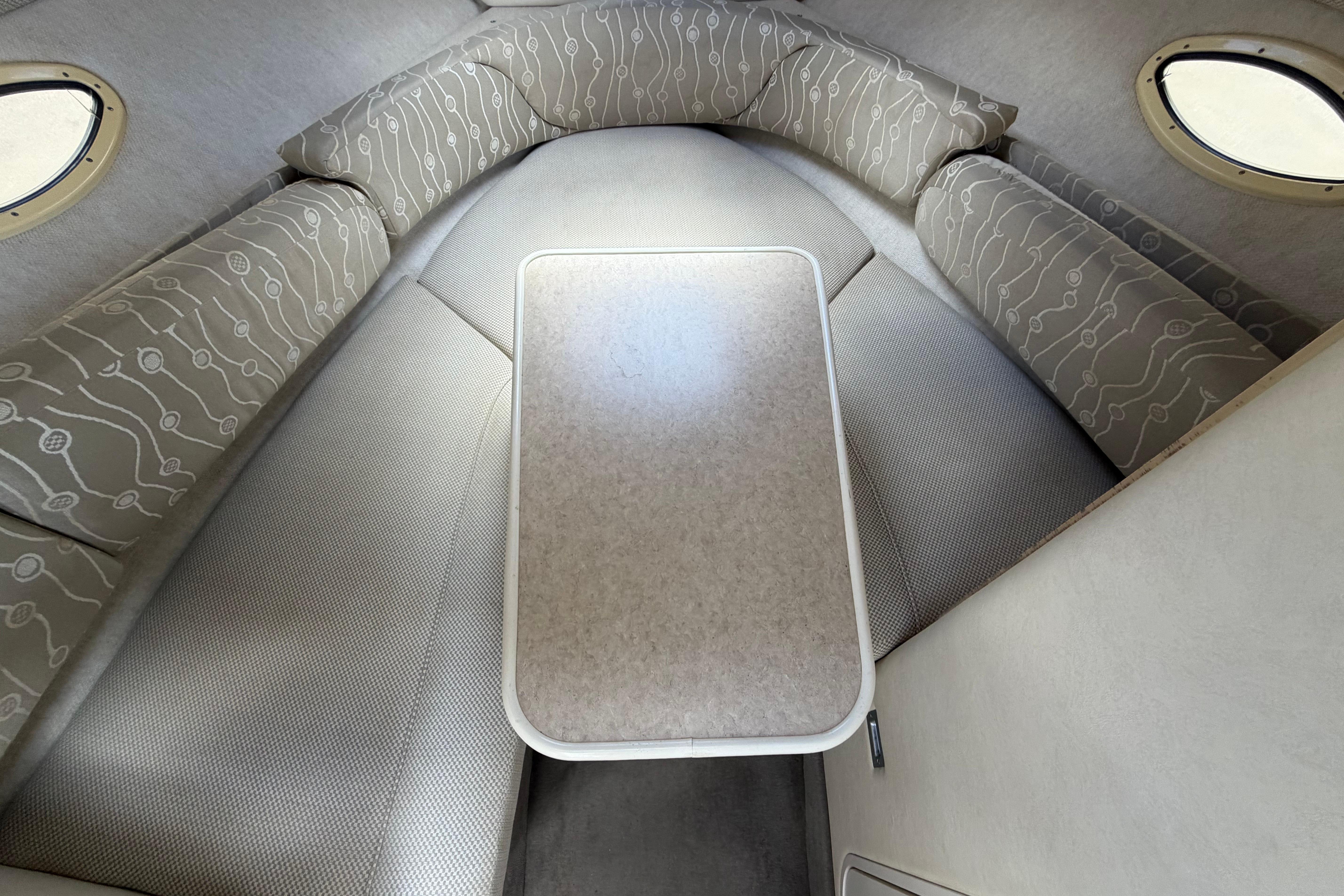 Interior cabin of 2006 Sea Ray 250 Amberjack with cushioned seating and table.