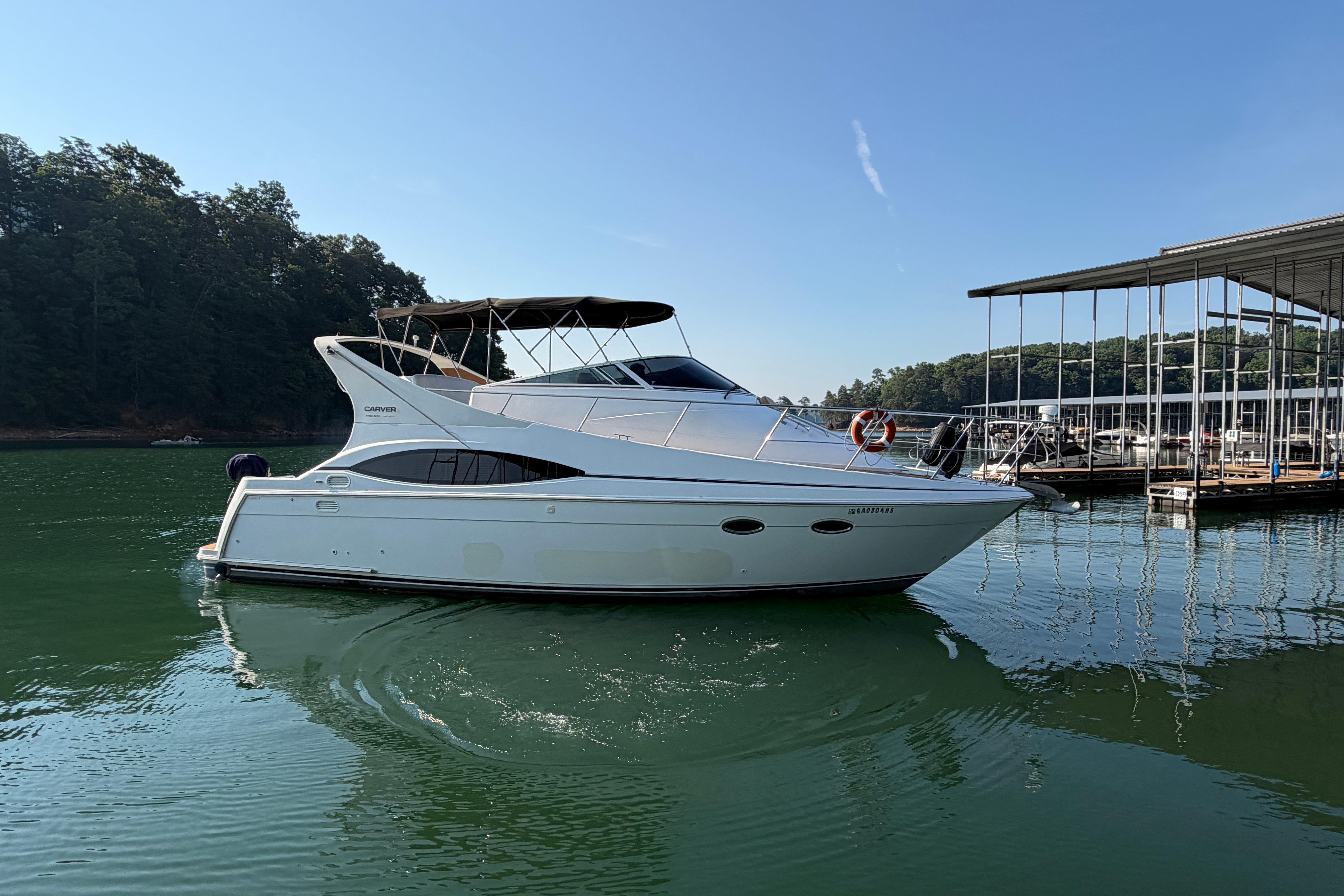 2003 Carver 350 Mariner yacht docked on a serene lake under clear blue skies.
