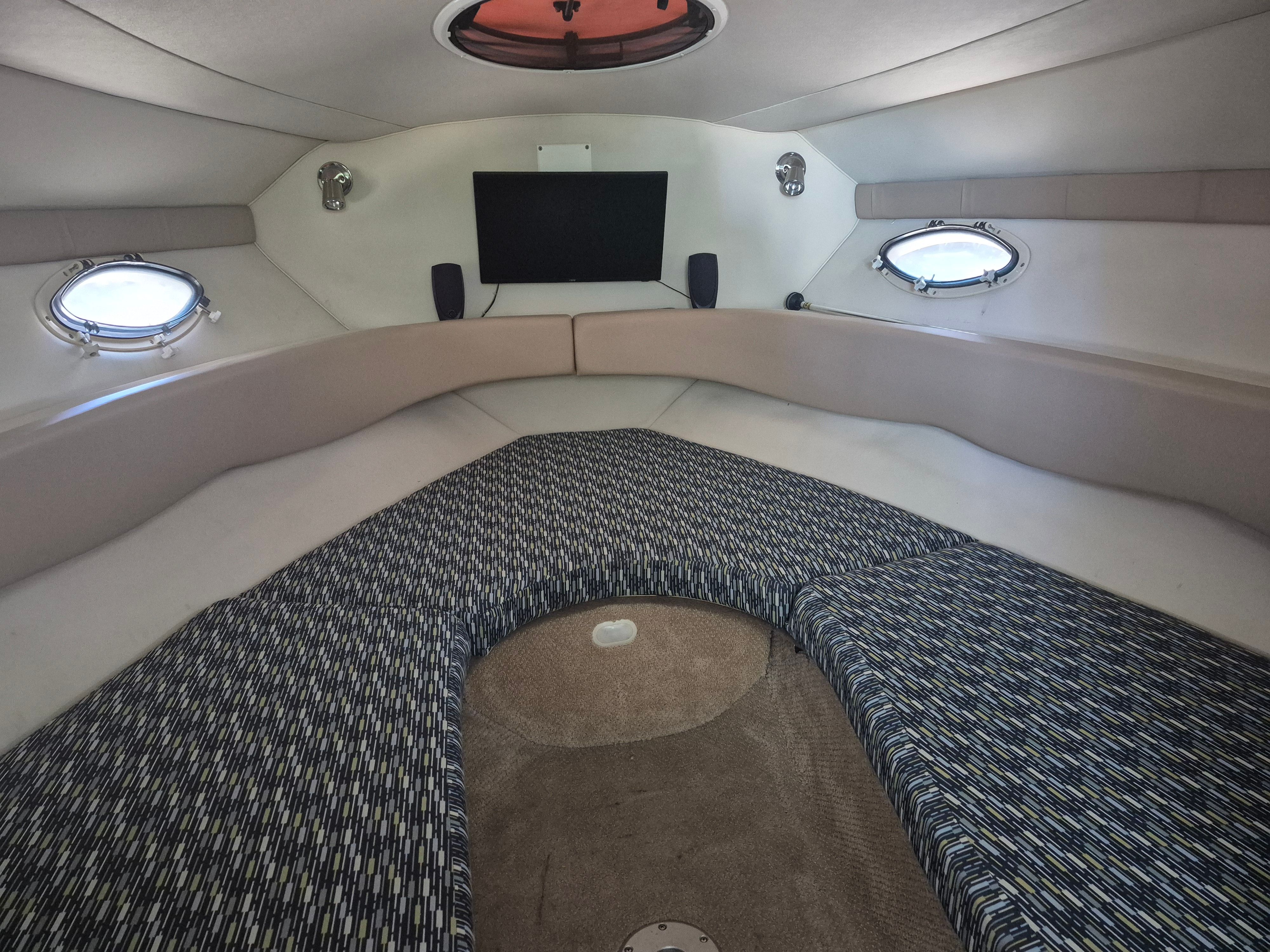 Interior of a 2004 Larson Cabrio 274 with cushioned seating and portholes.